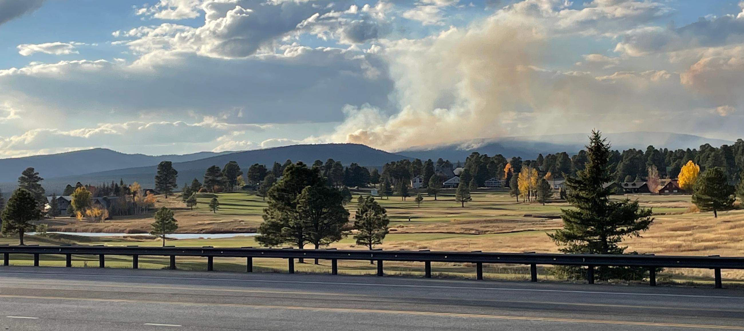 Photo shows a neighborhood in Pagosa Lakes, CO with smoke from the Trail Springs Fire behind it