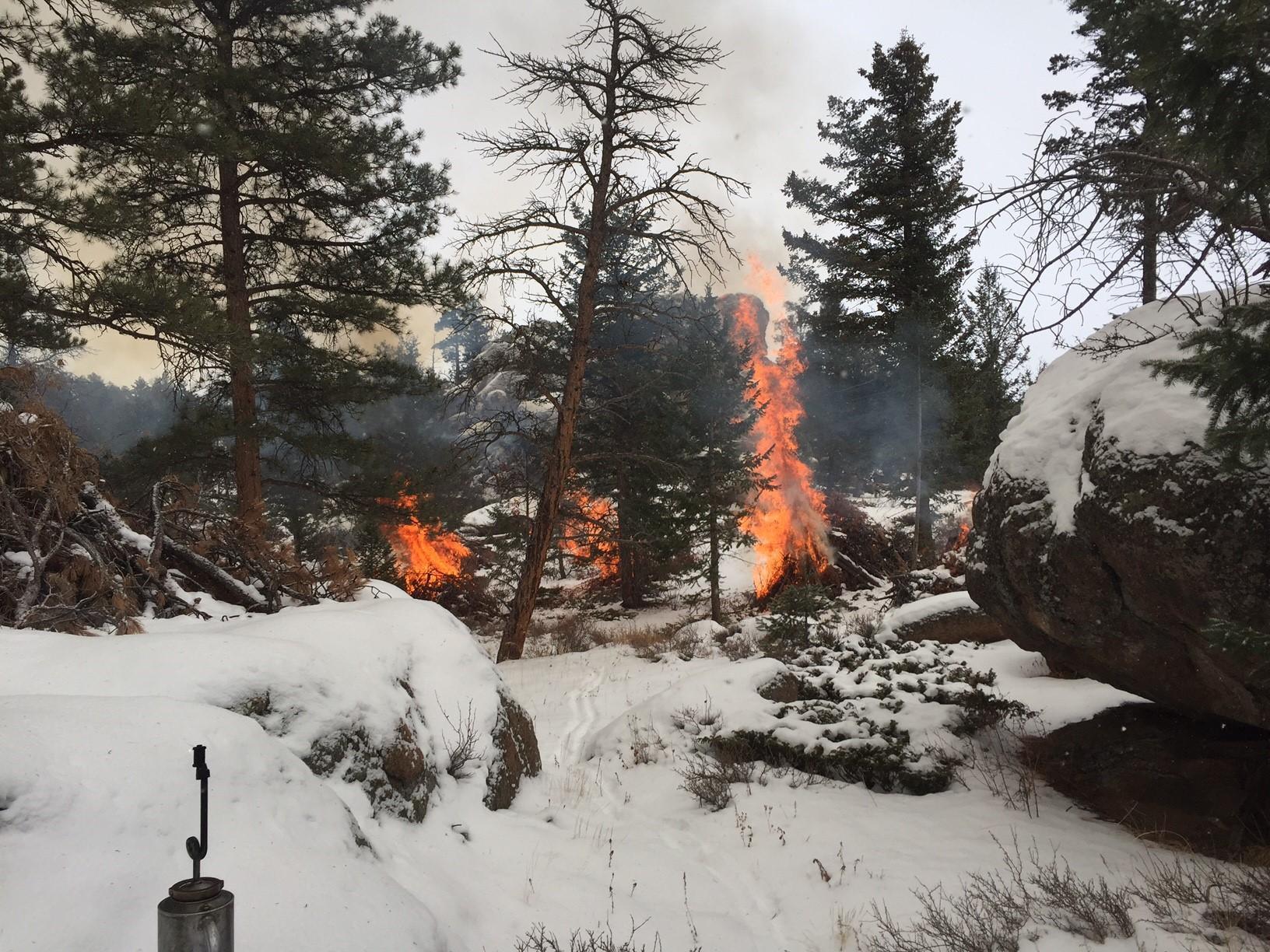 Pile burning in snow with smoke, flames