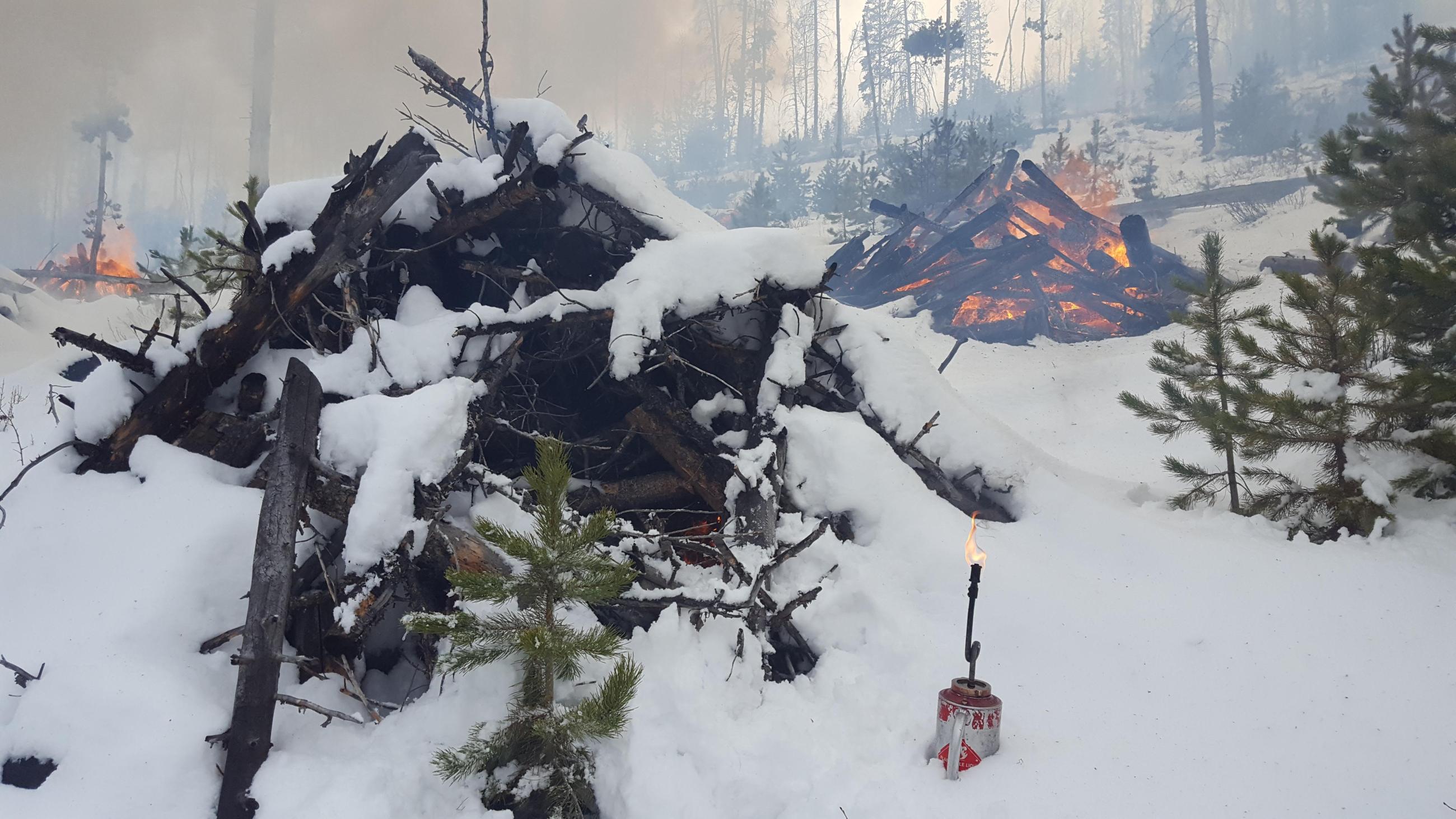 Pile burning in snow with smoke, flames