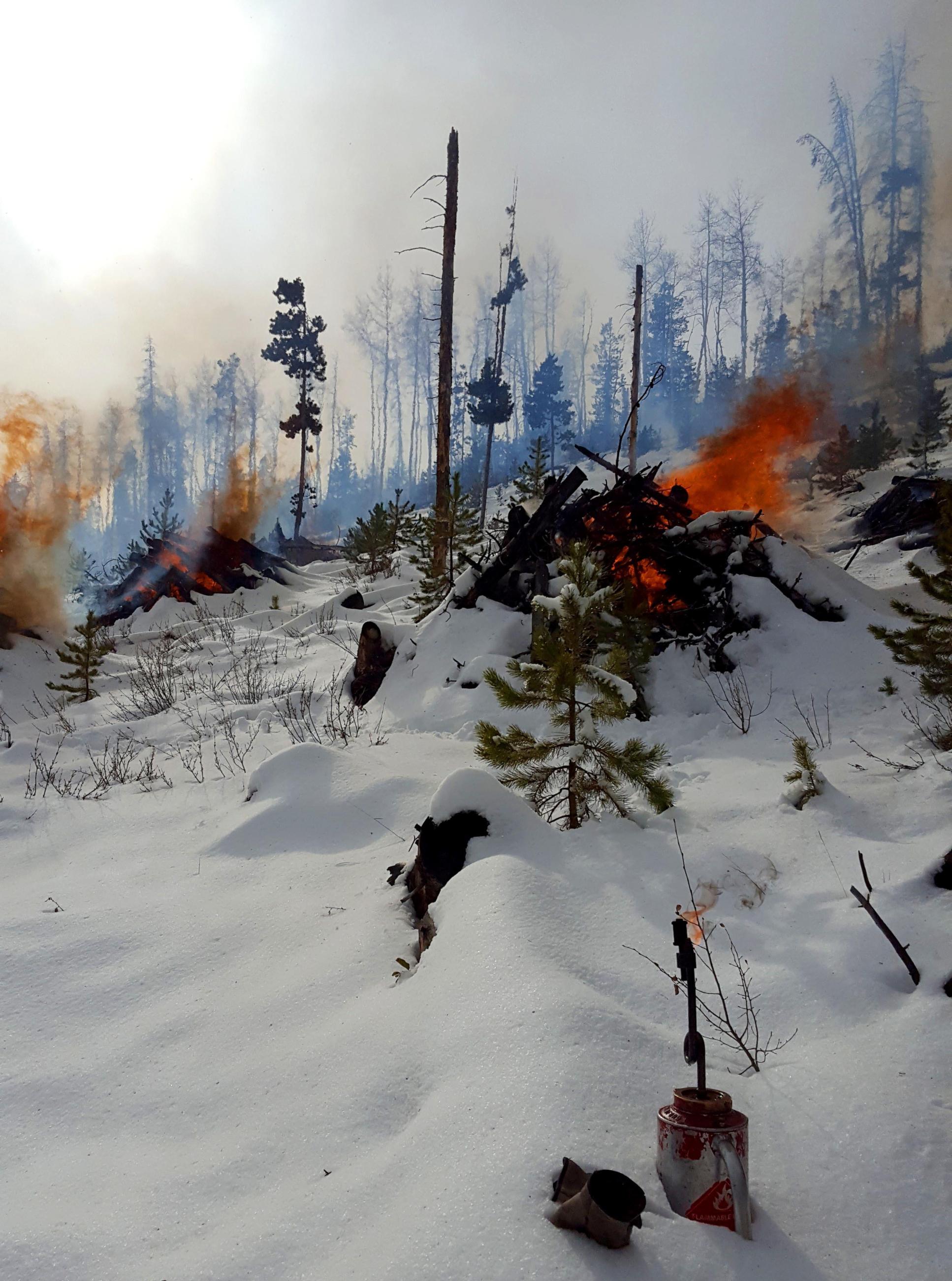 Pile burning in snow with smoke, flames