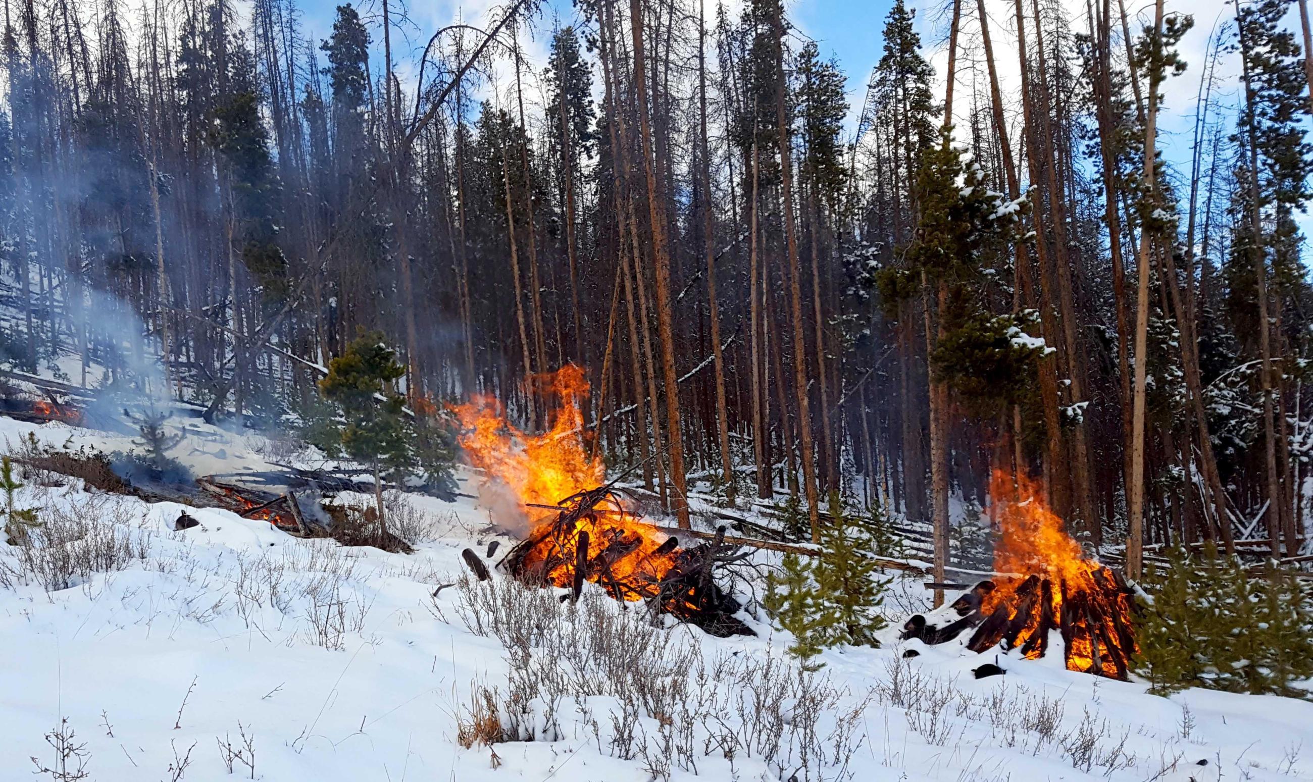 Pile burning in snow with smoke, flames