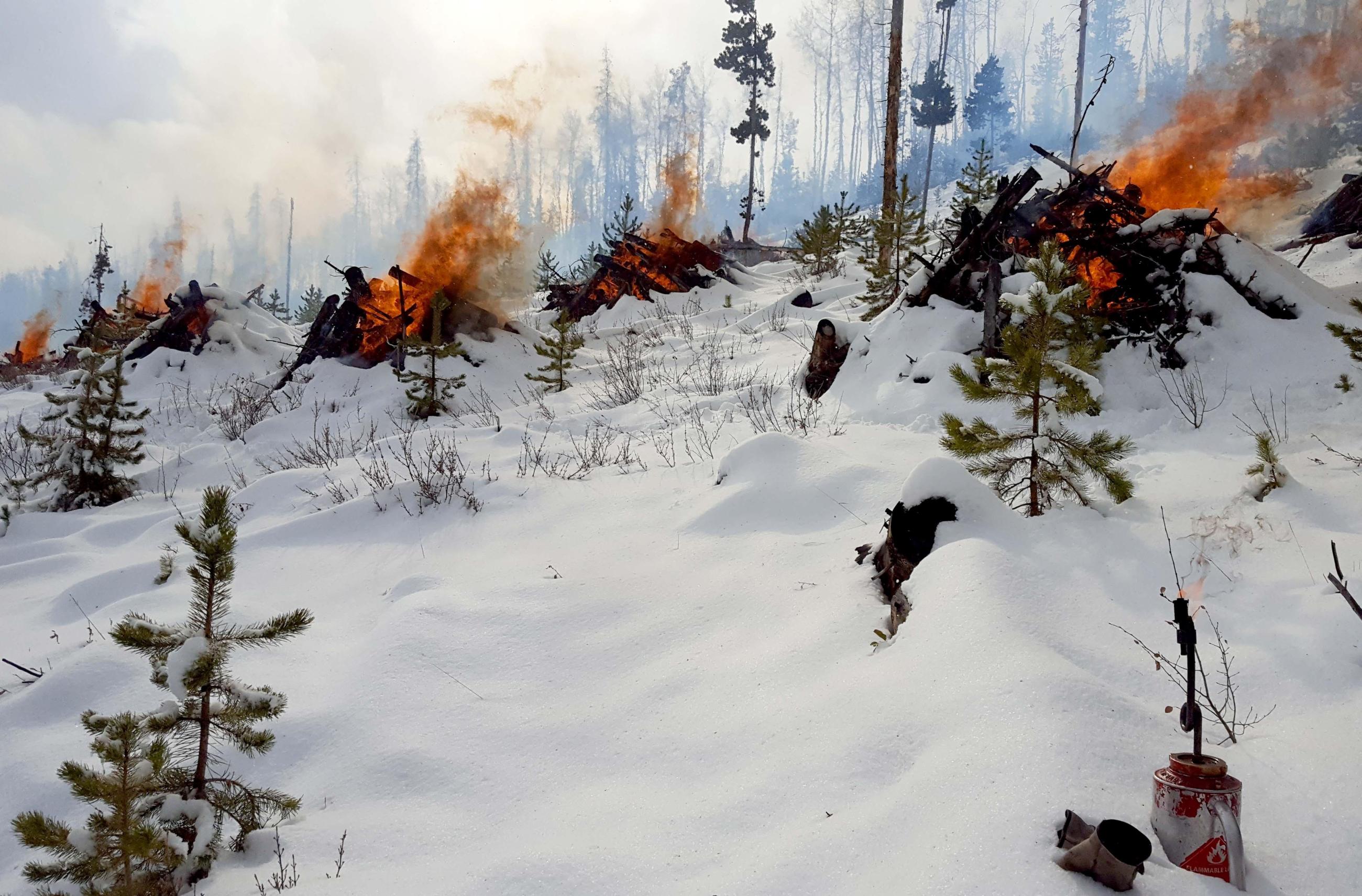 Pile burning in snow with smoke, flames