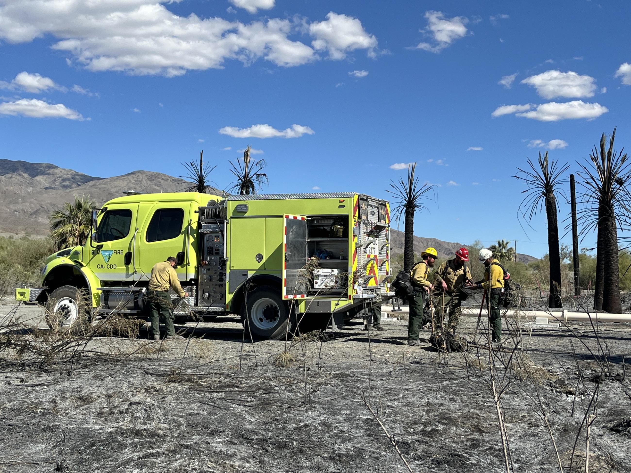 A BLM fire engine with firefighters standing nearby.