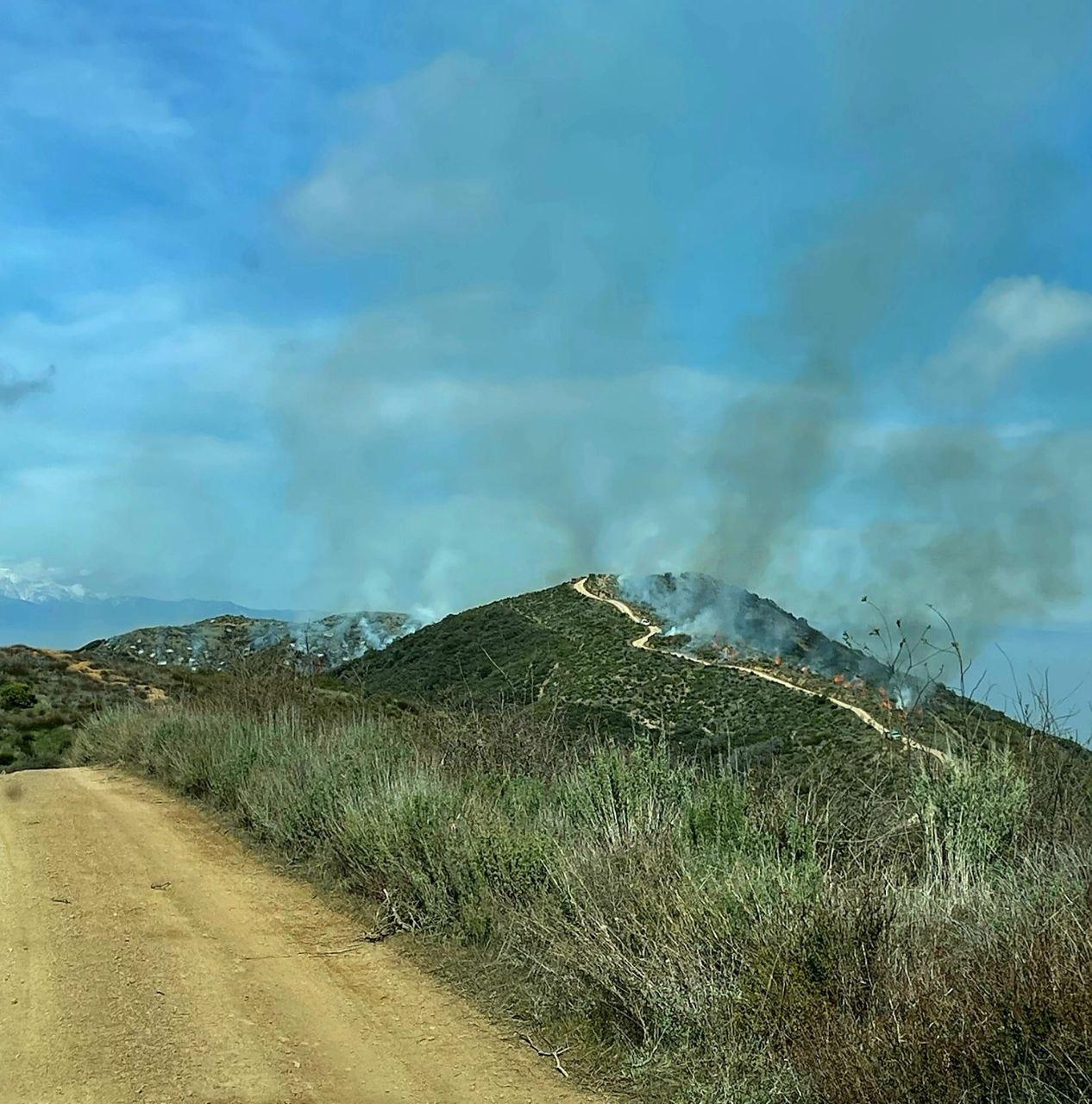 Image of fire and smoke on a ridge with firefighters working on the prescribed burn.