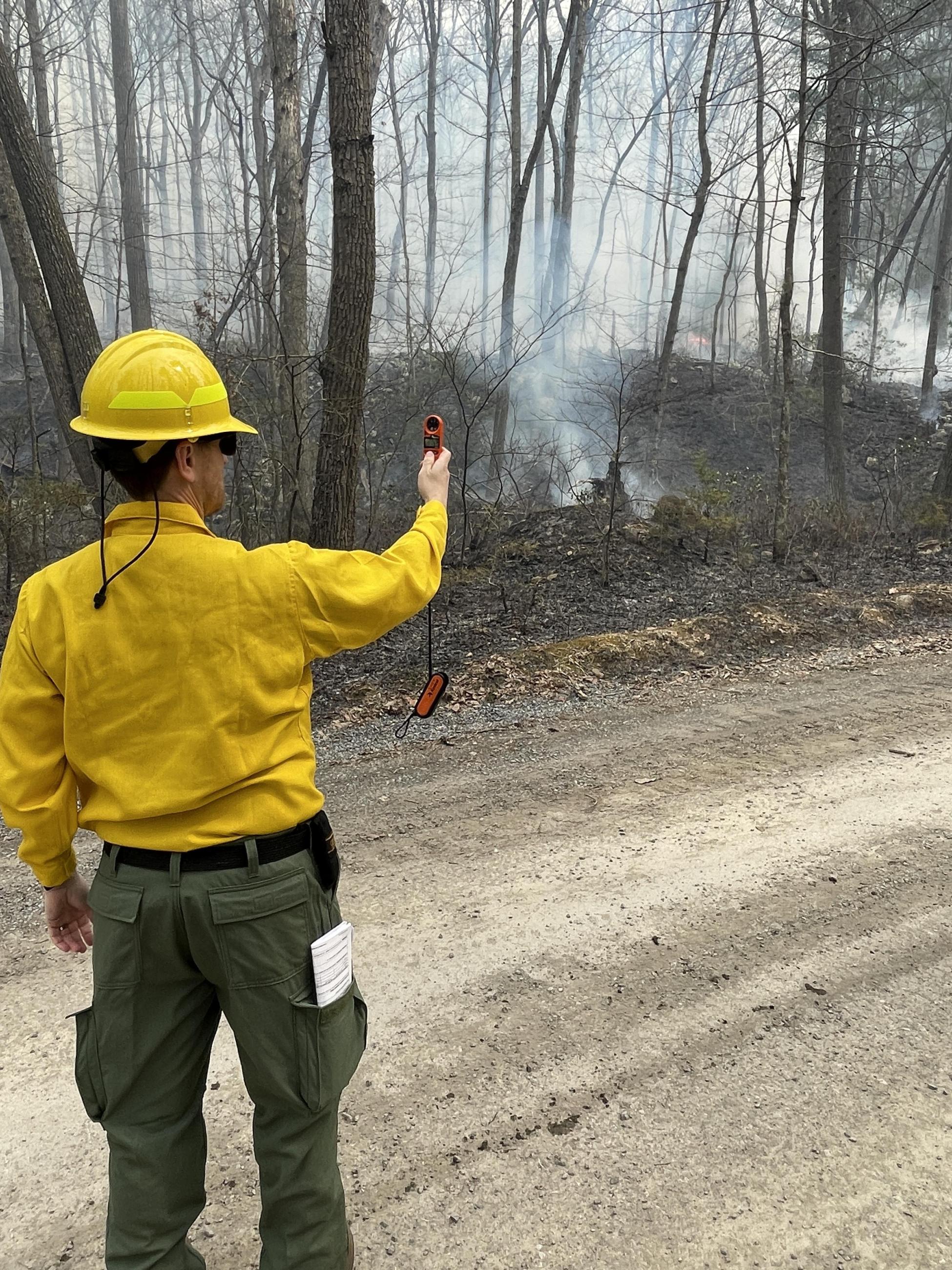 Firefighter standing in the road holding weather meter