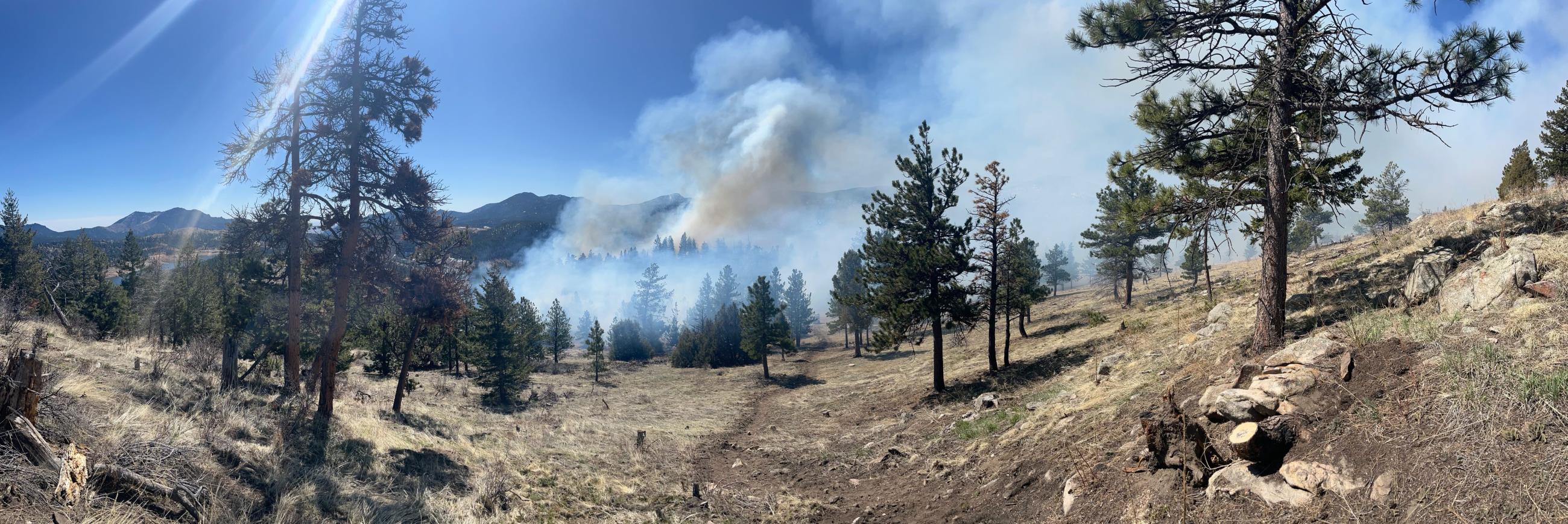 A panoramic shot of smoke coming from the center of the prescribed burn area