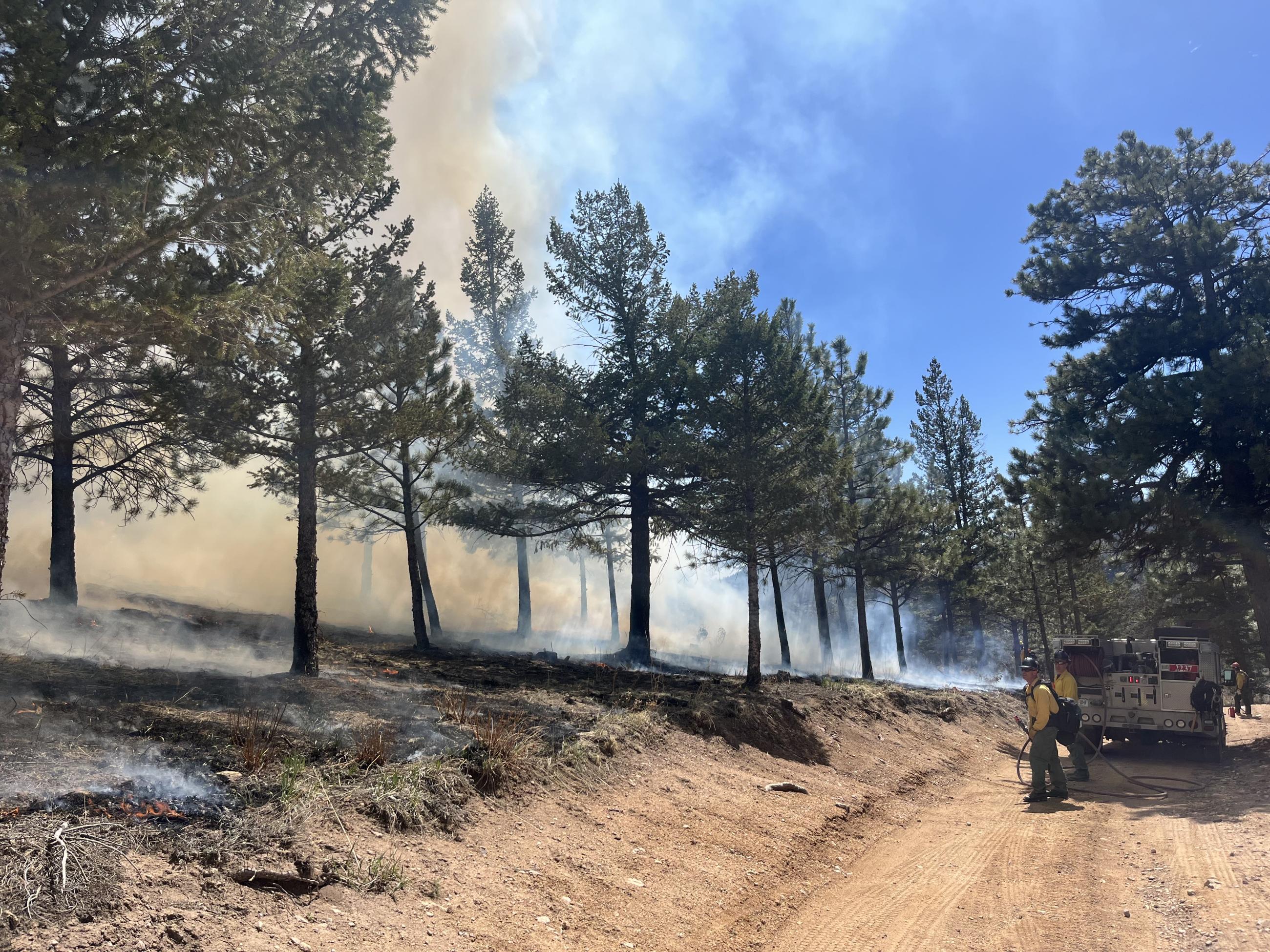 A fire truck works along the road with smoke uphill during the Forsythe II prescribed fire.