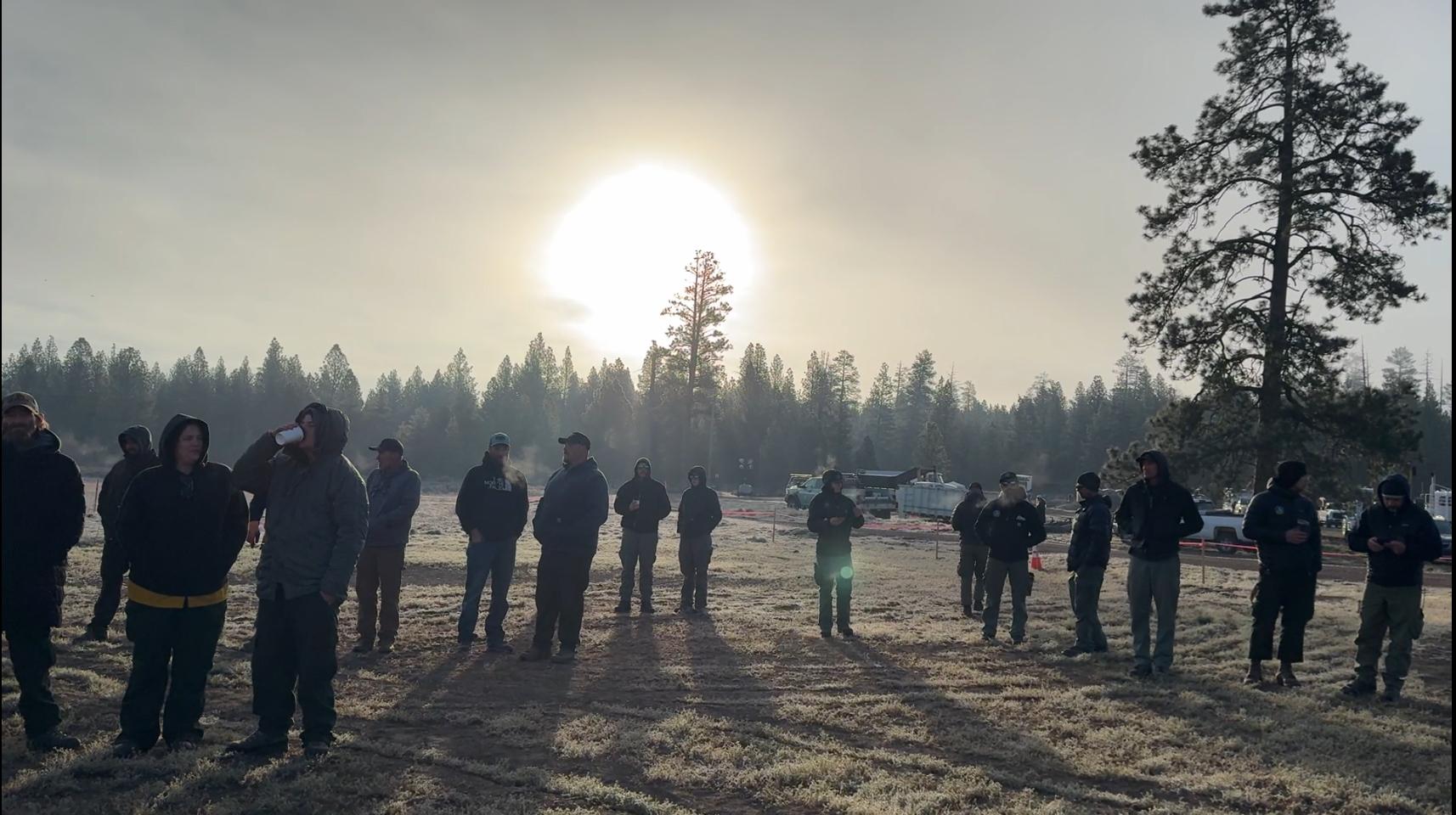 A group of firefighters cast a silhouette with the rising sun