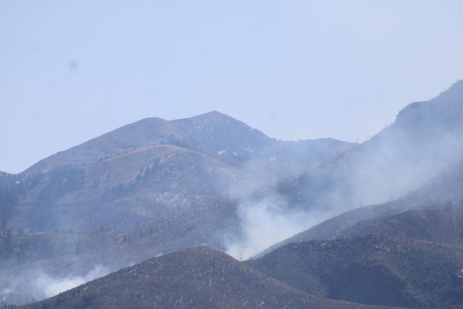 Smoke rises from between two mountain ridges.