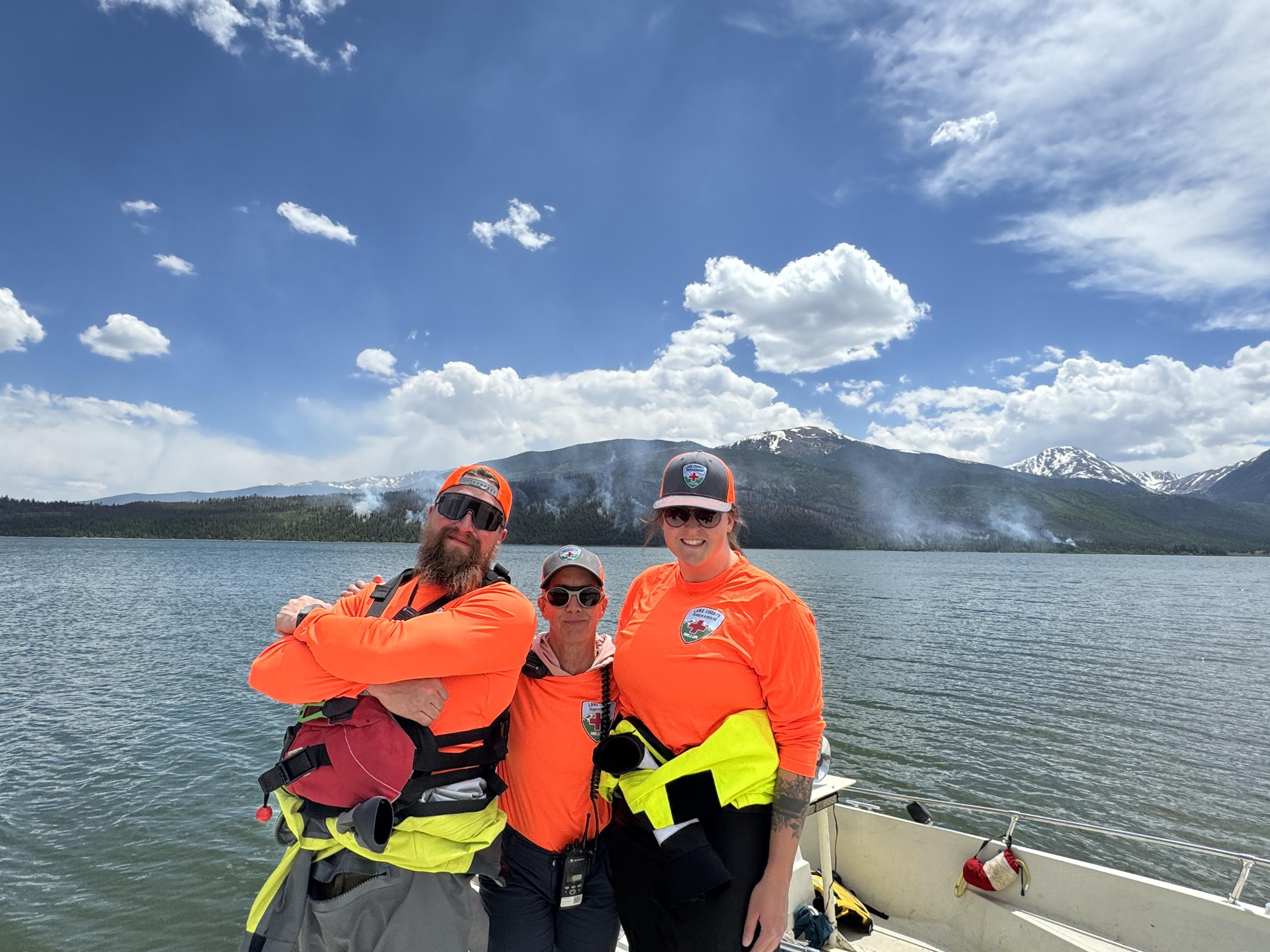Three members of the Lake County Search and Rescue Team on a boat on Twin Lakes with the Interlaken Fire in the background.
