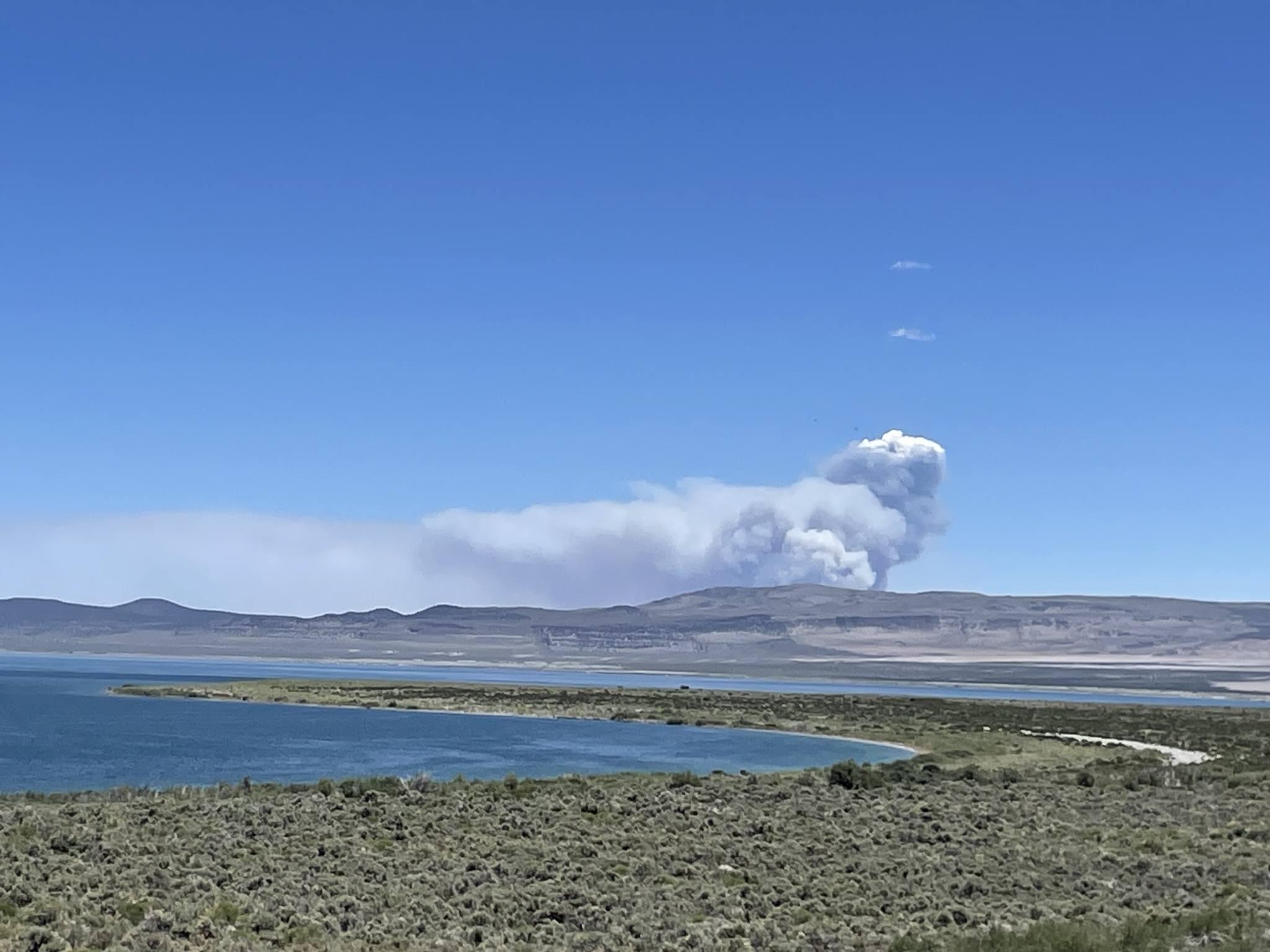 Pizona Fire, as seen from South Tufa area at Mono Lake. Smoke is visible in the distance over low hills with otherwise blue sky. 