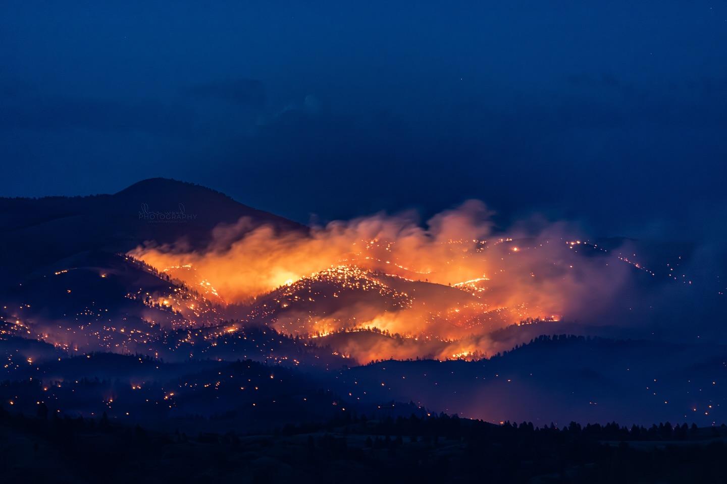 Rolling hills at night, lit with flames and smoke