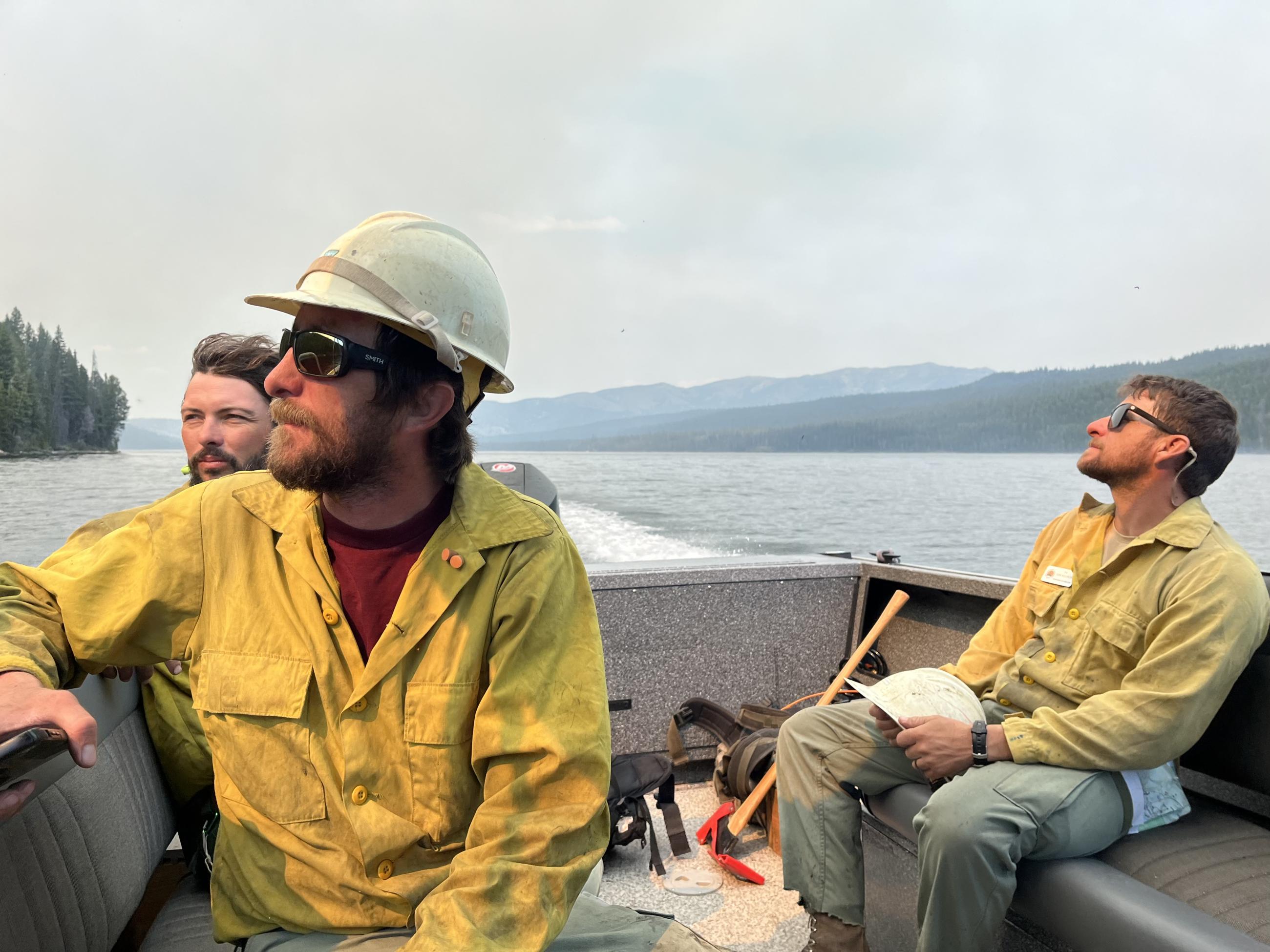 Firefighters siting in boat traveling across a lake