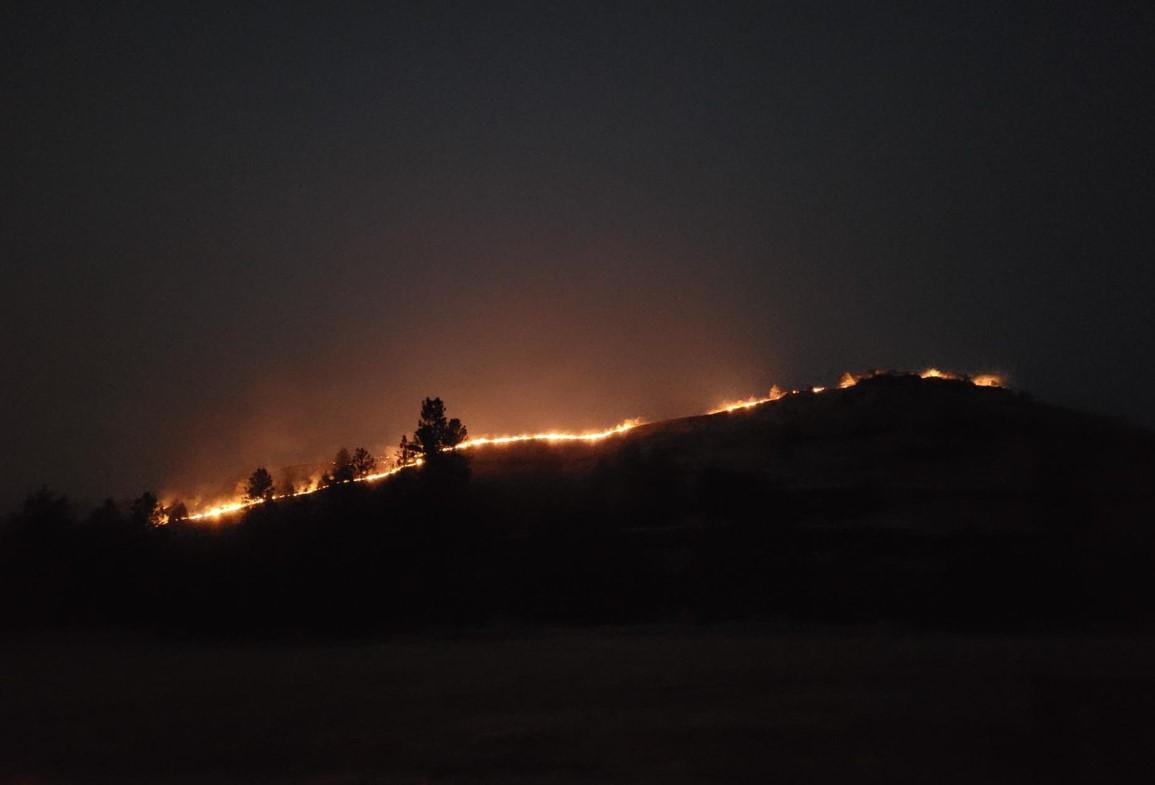 Image of flames cresting a ridge at night.