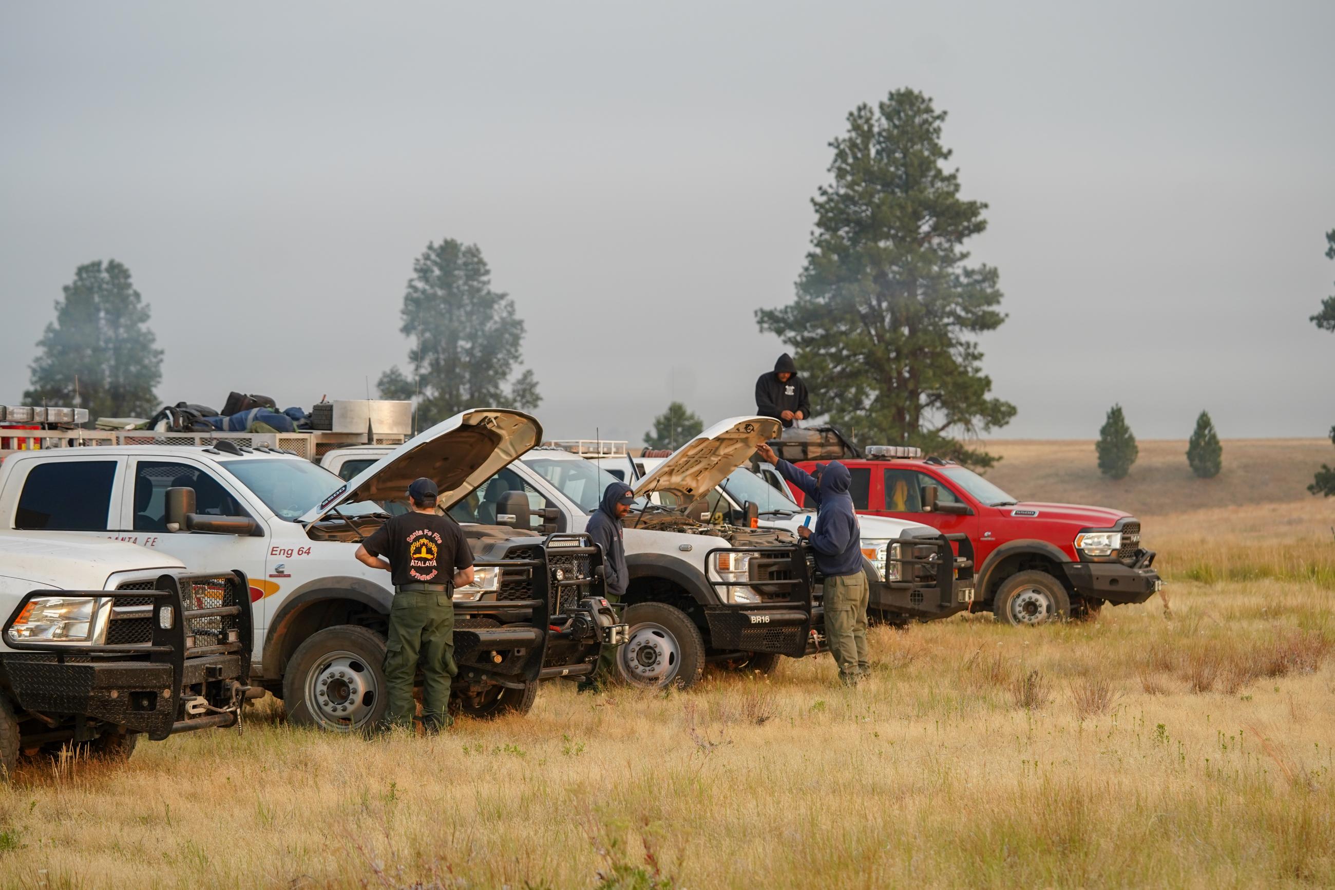 Image of wildland fire engines staging in a grassy field. 