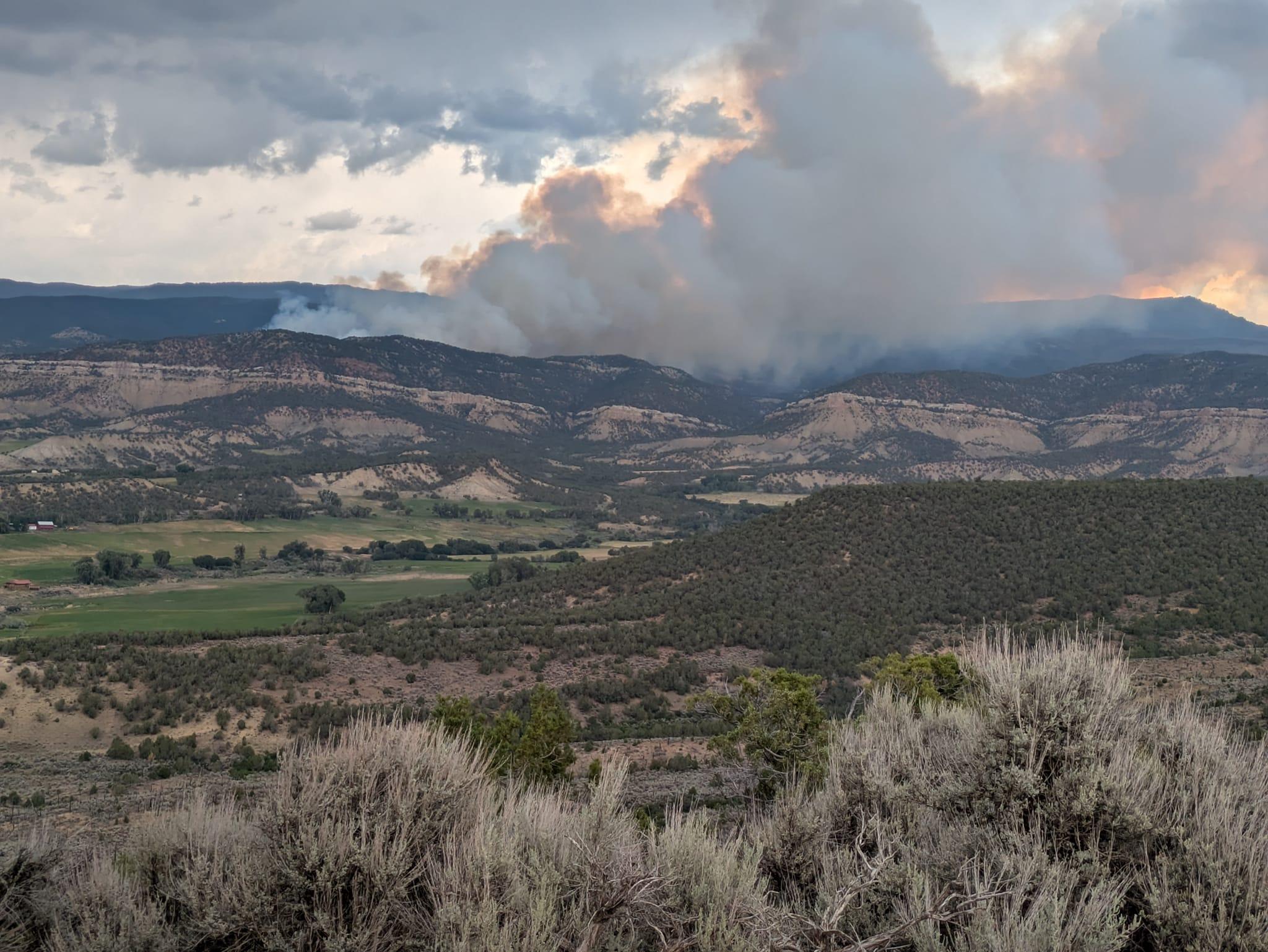 Photo of rolling high desert hills with a large plume of smoke rising up - Source: Debbie Williams Christner
