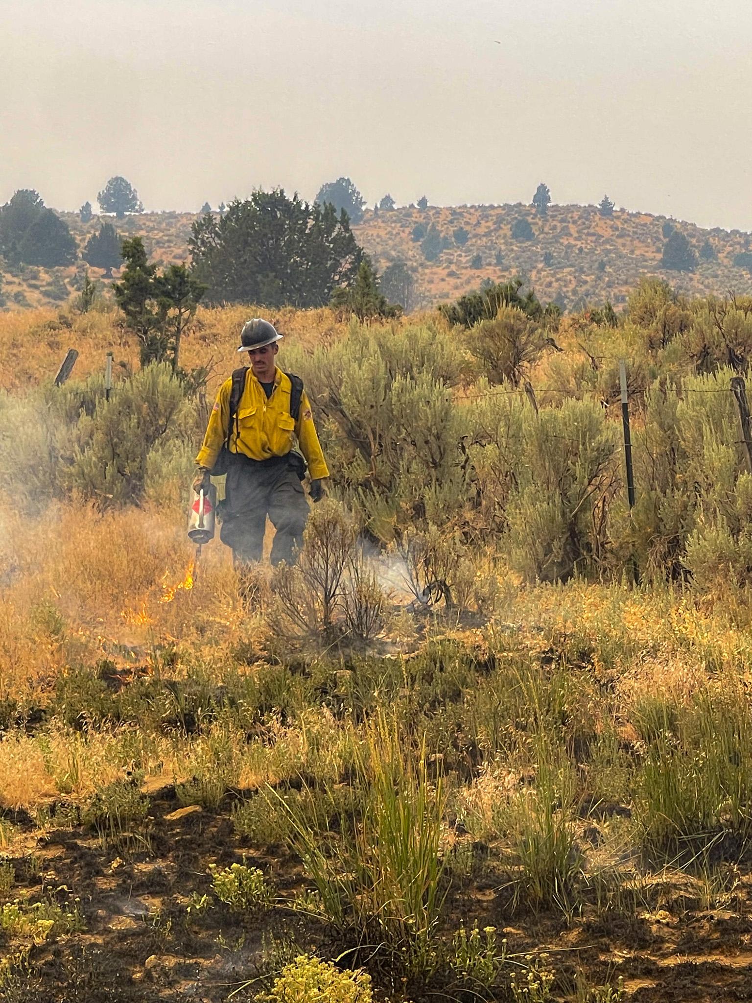 firefighter lighting grass with torch