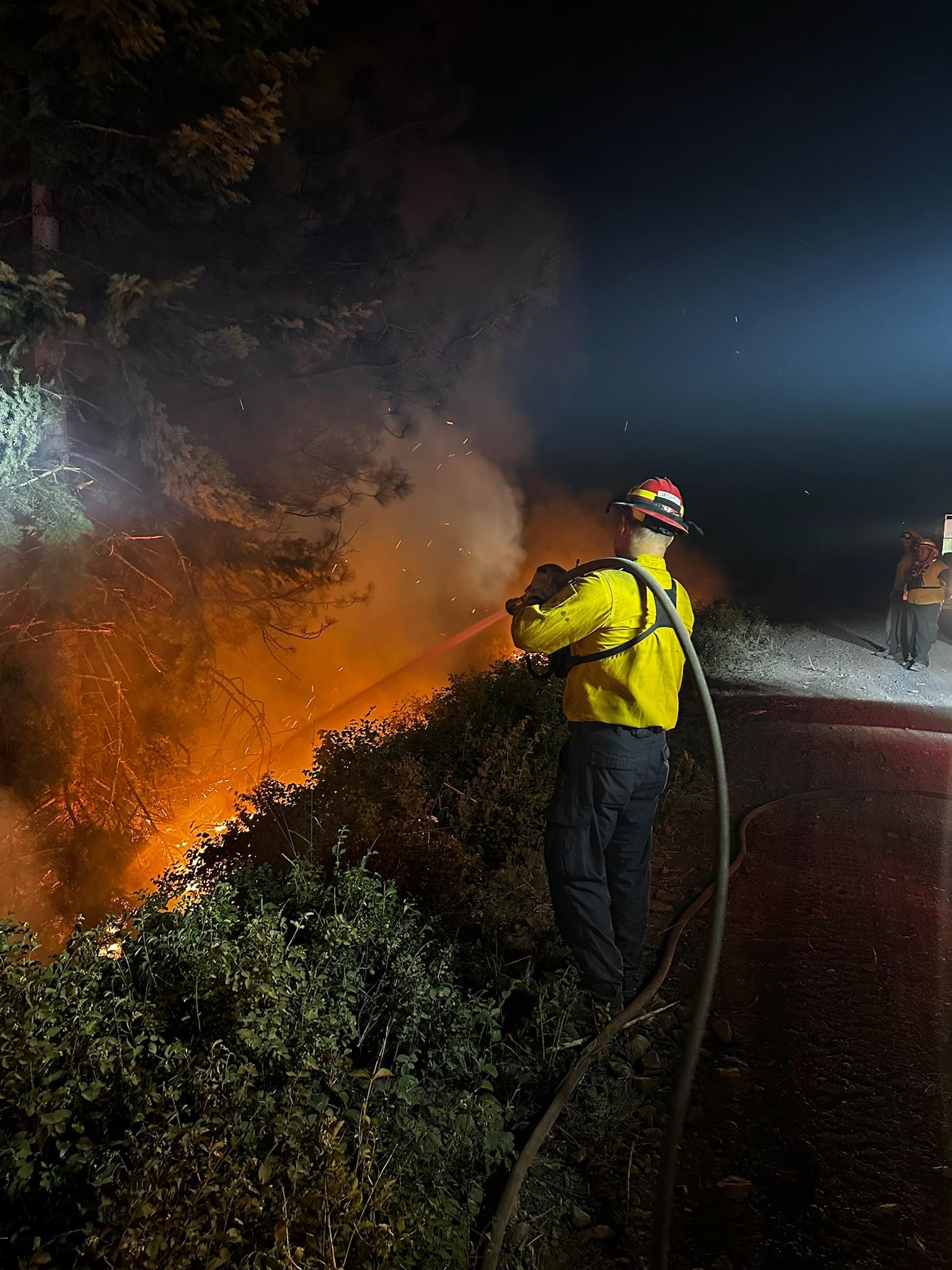 A firefighter sprays water Night Operations - Lone Rock Fire