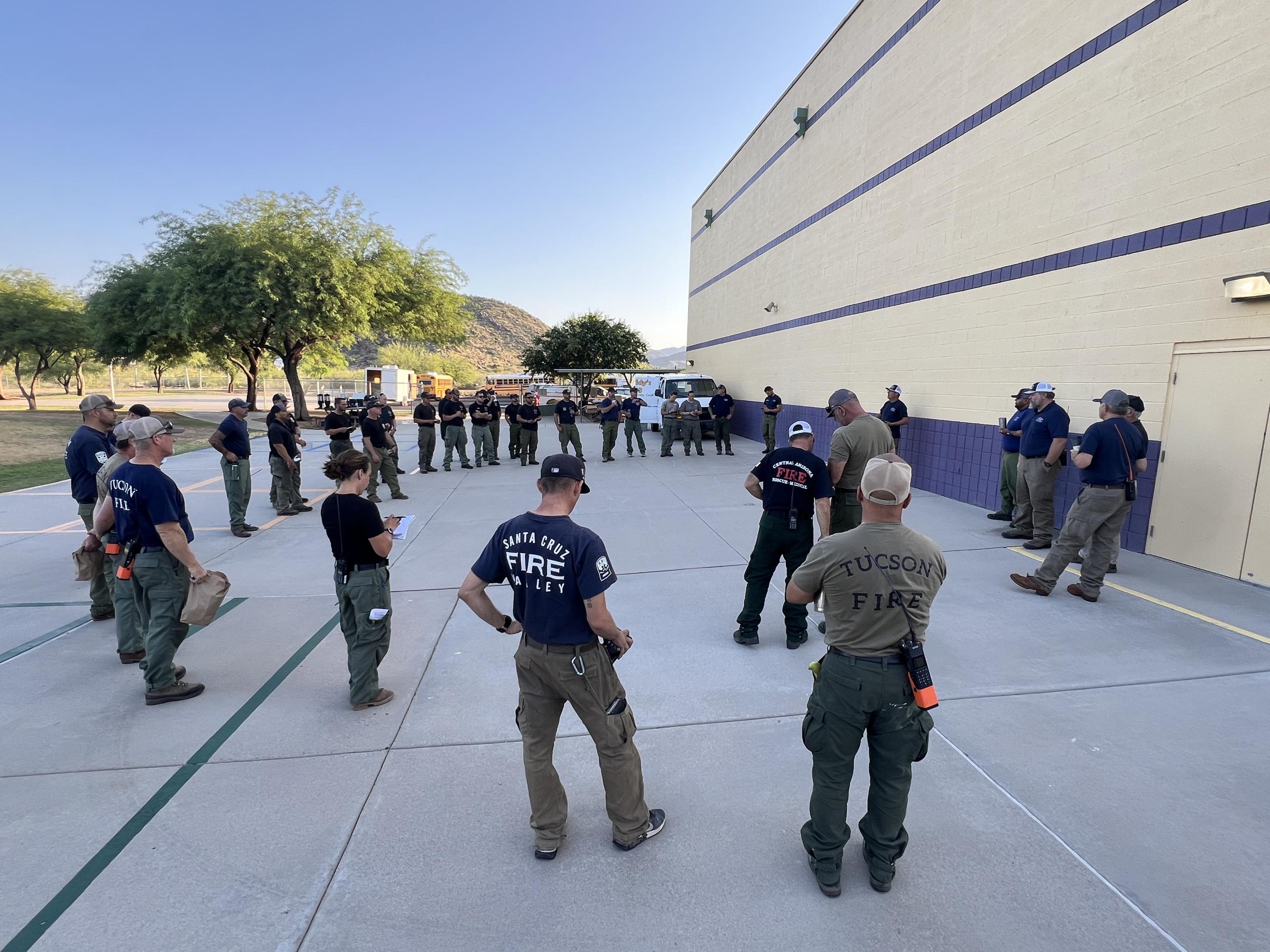 Firefighters stand in a circle to hear the plan for the day