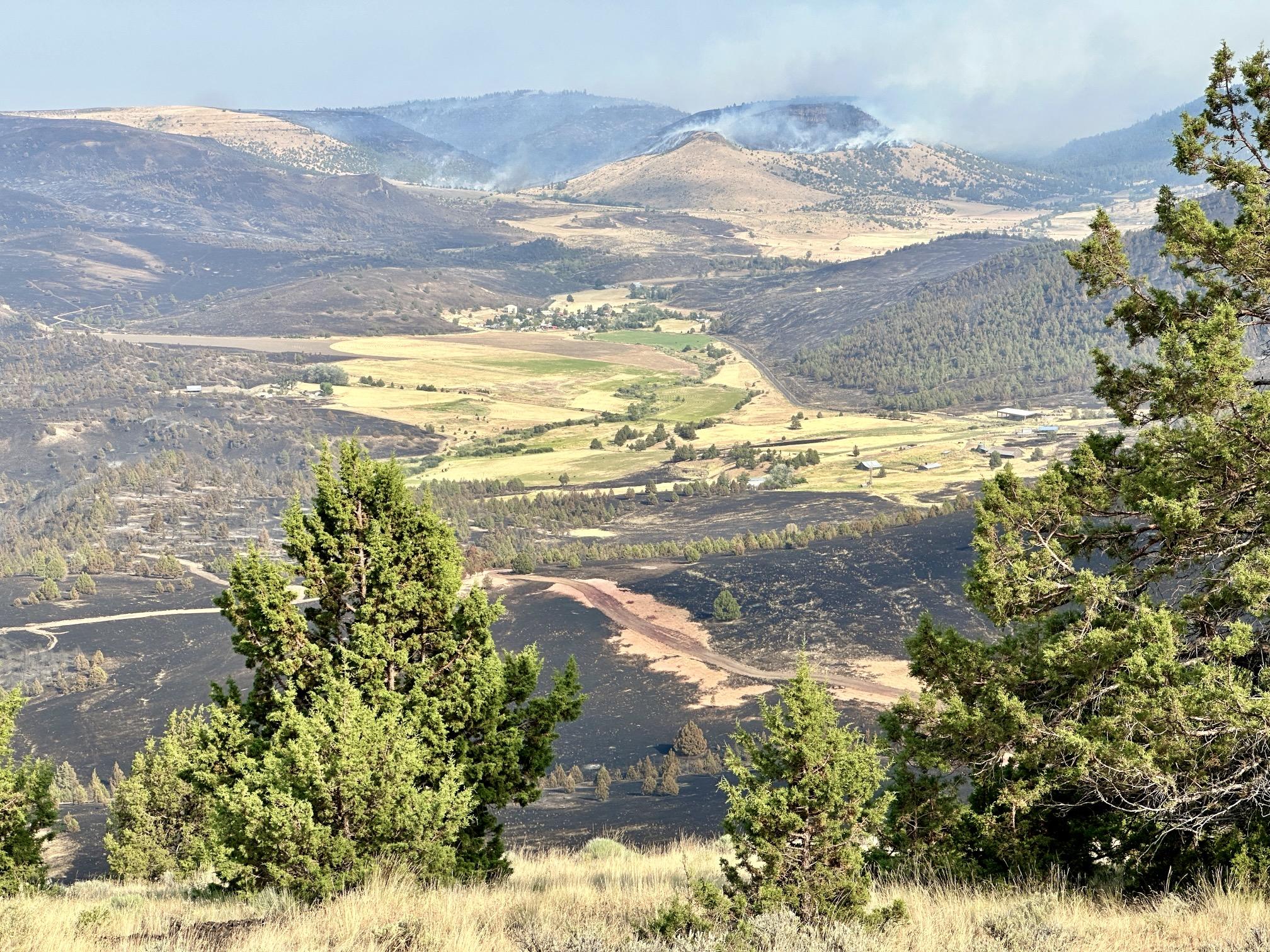 This landscape view shows the Lone Rock Fire burning around residences and rances