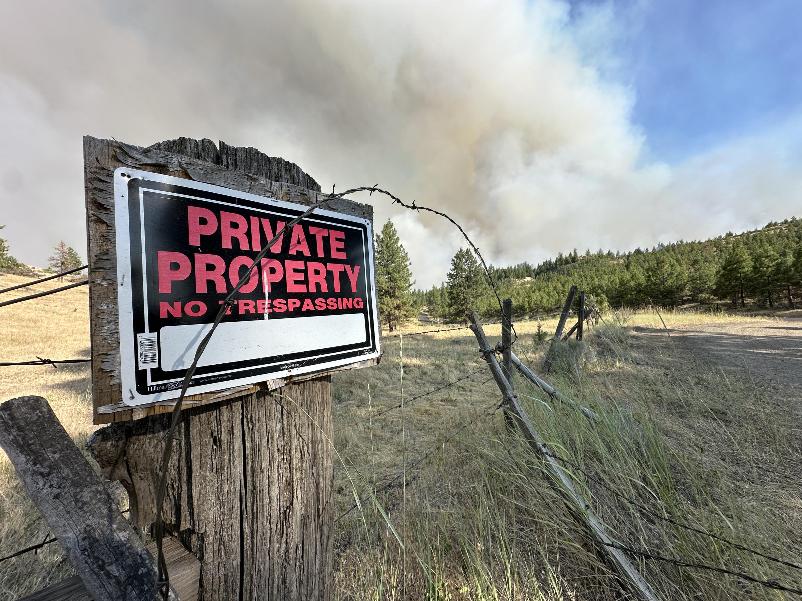 A smoke column can be seen near private property on the Lone Rock Fire