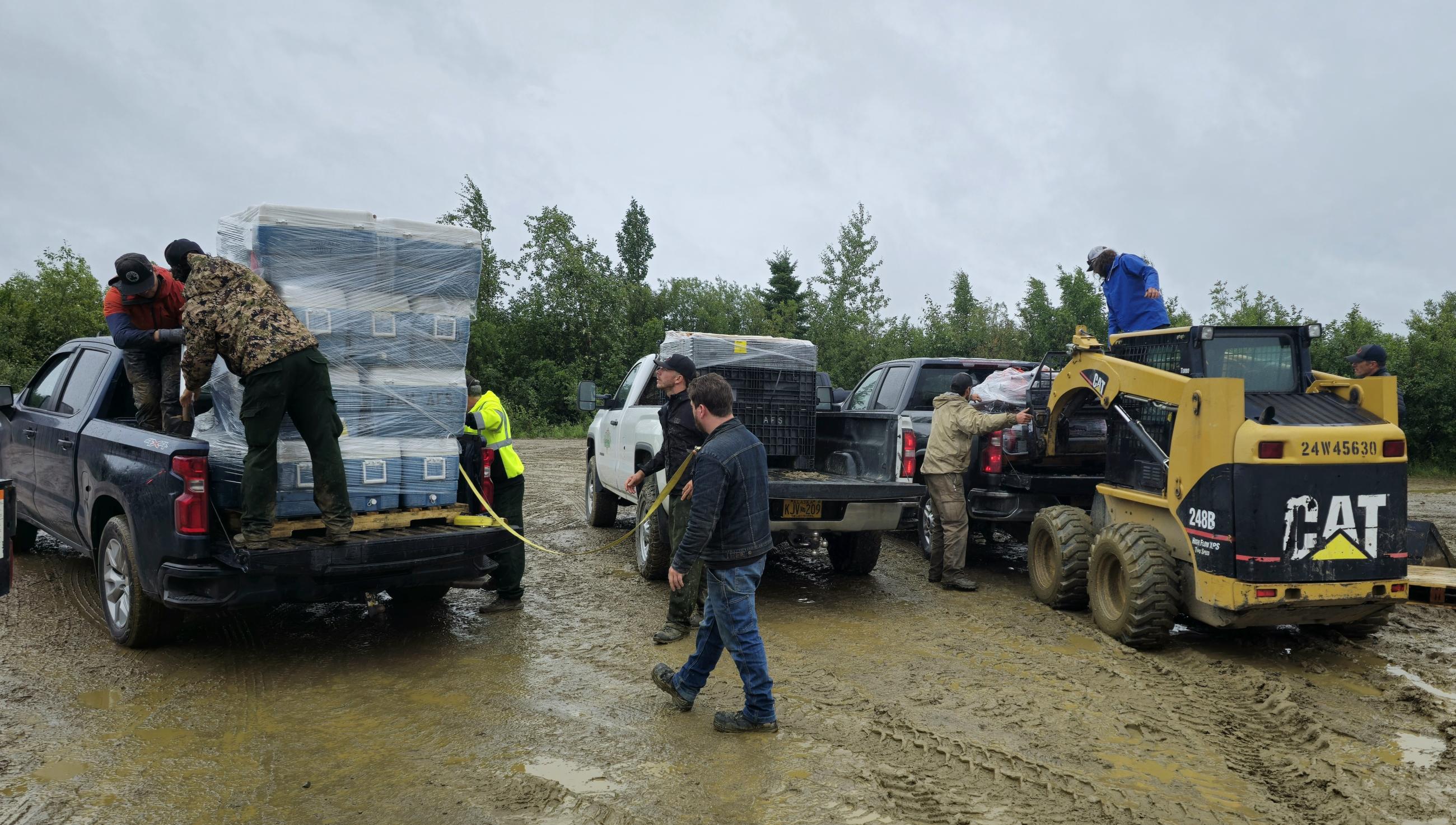 Firefighters and trucks with gear in muddy parking lot