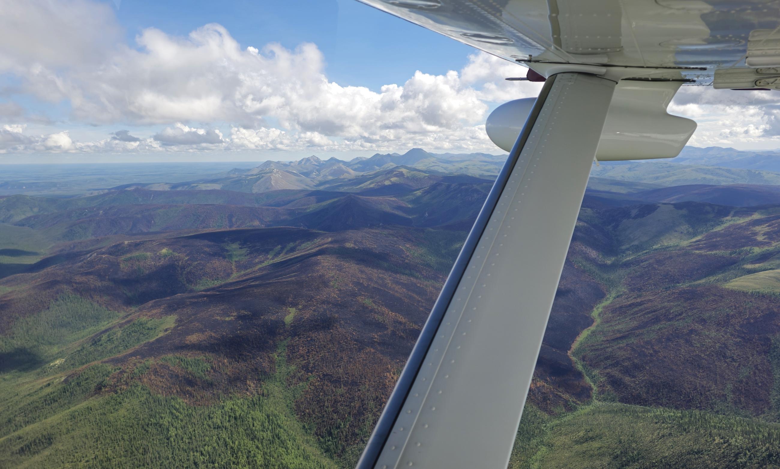 looking under wing to mtns and black burn into green