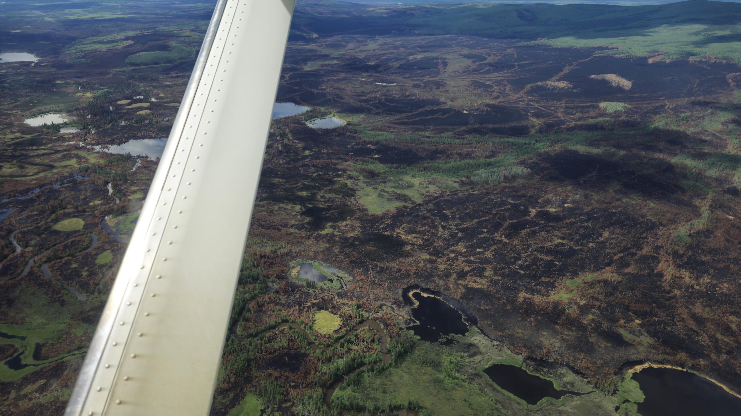 Look out wing small round lakes inside burned area out in the distance