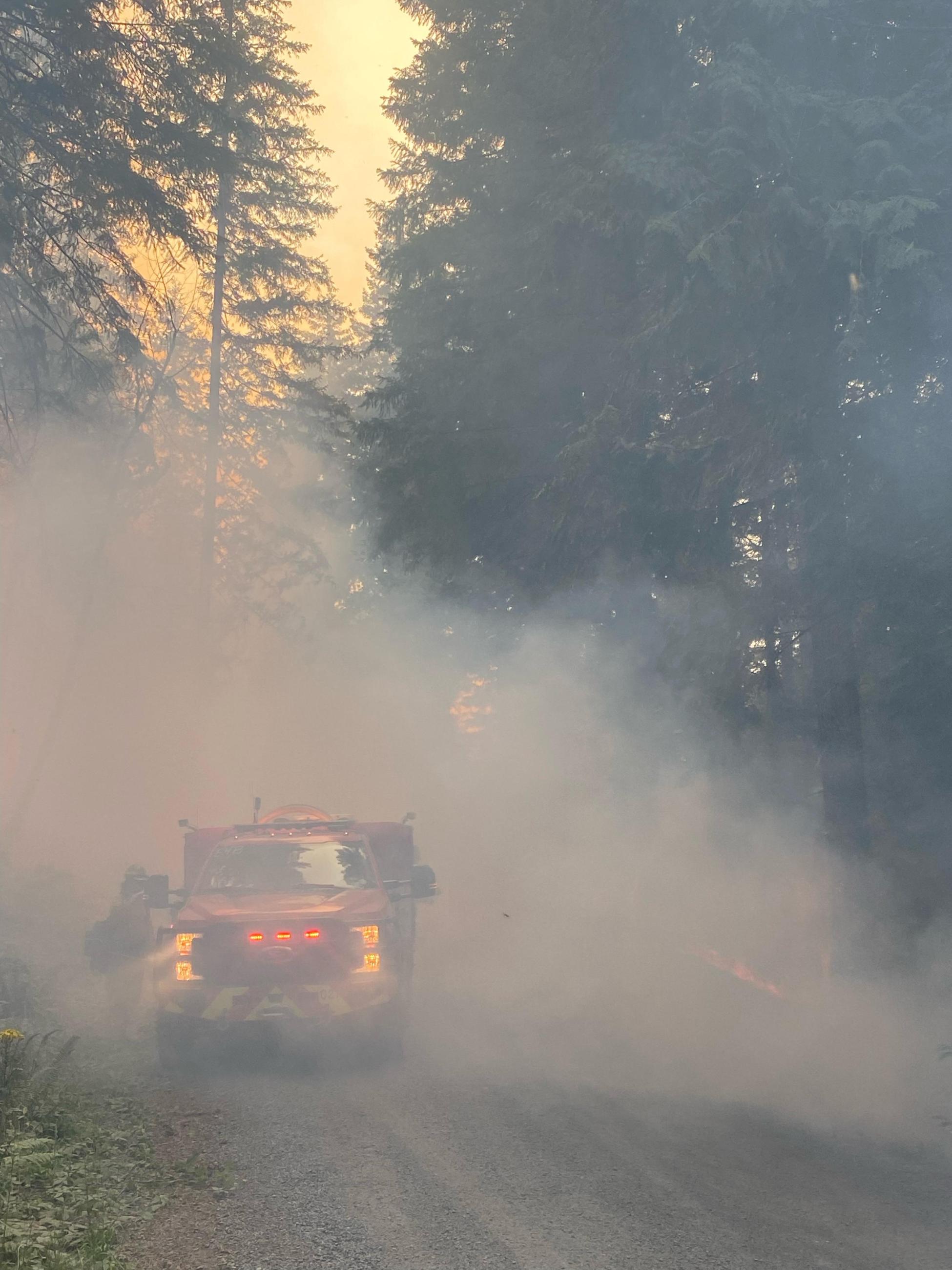 very smoky conditions along a forest road obscures a small fire truck