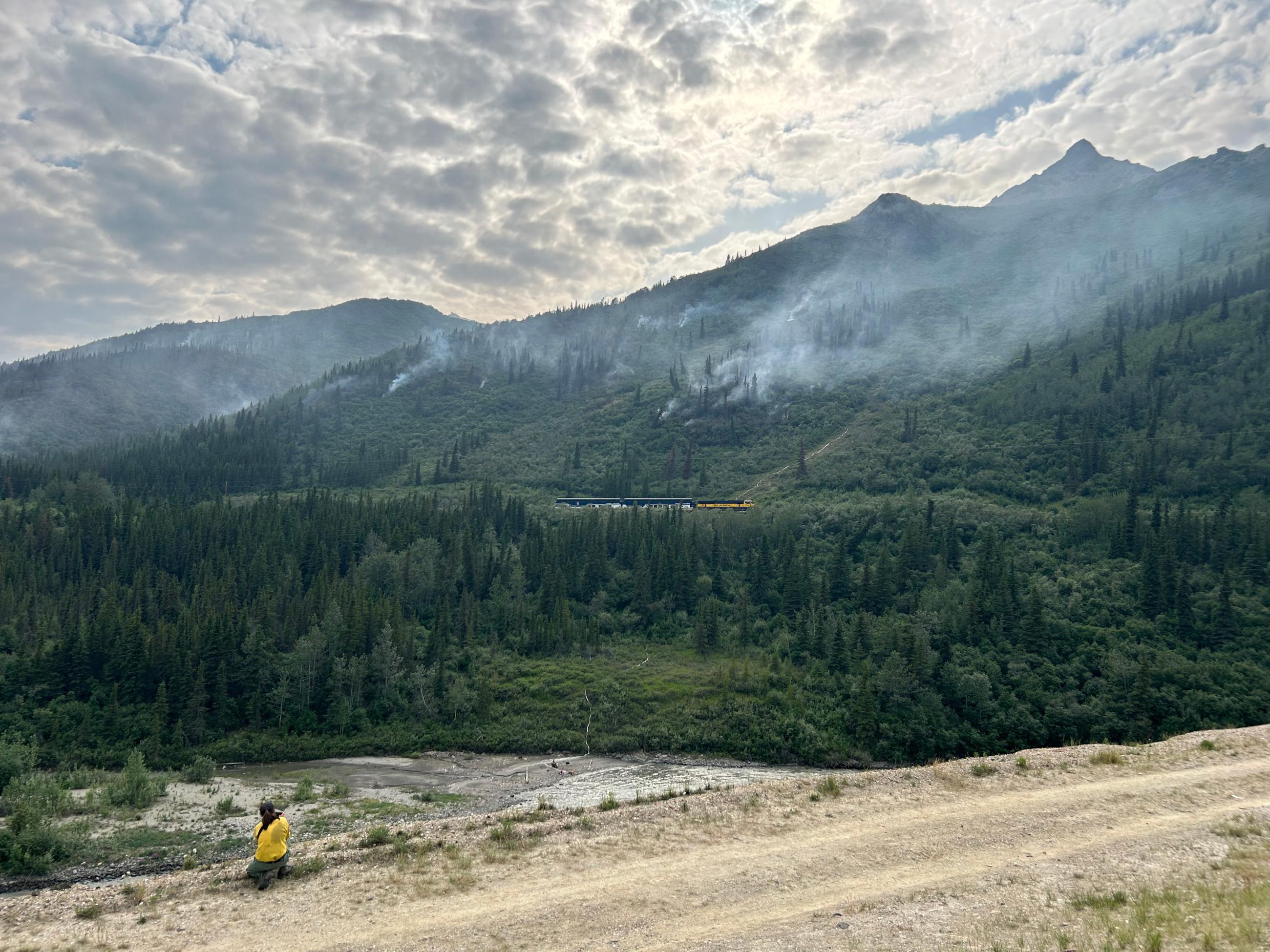 A train rolls through the fire area, a firefighter takes a photo.