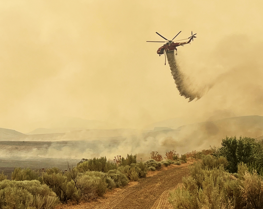 Helicopter dropping water over a grassland