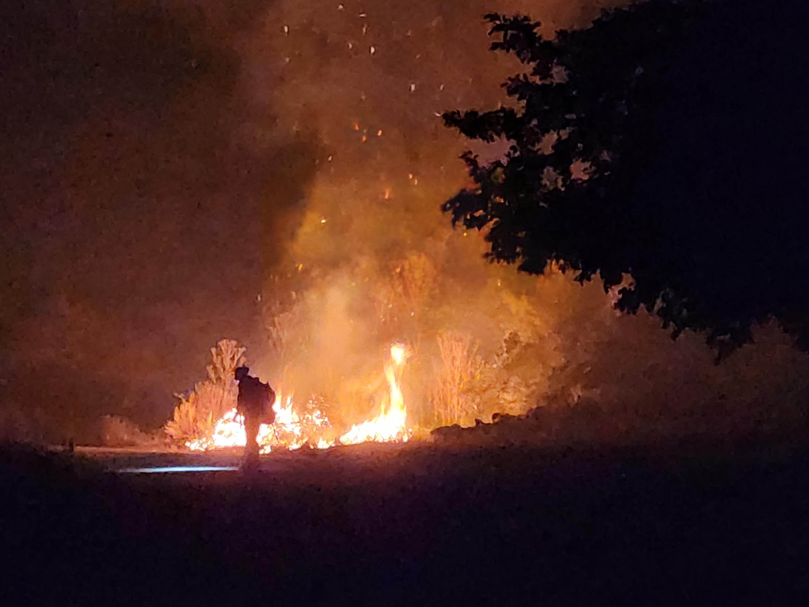 Cameo of firefighter working in the dark night, with active flames rising