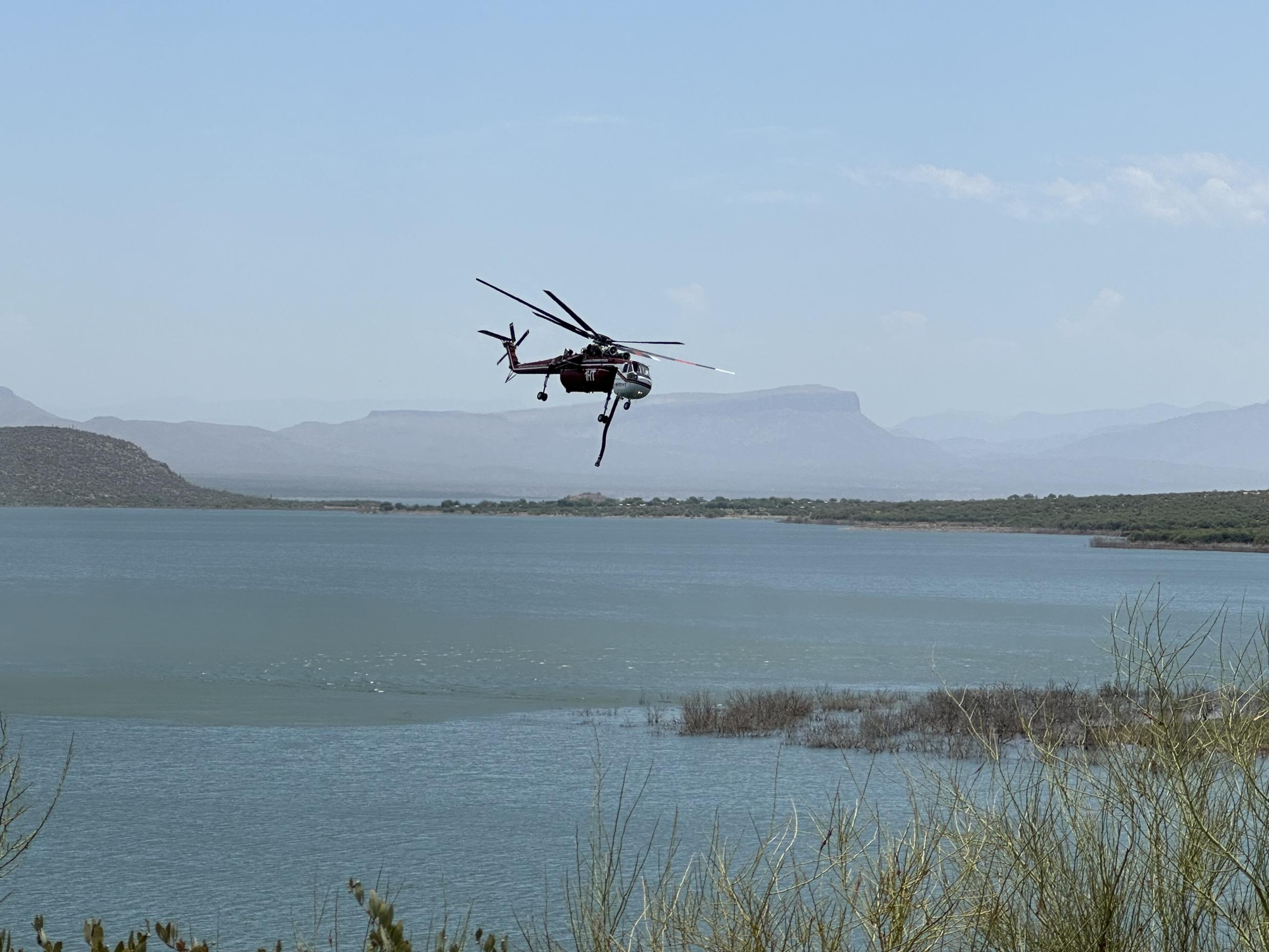 Helicopter drafting water from the lake to deliver to the fire