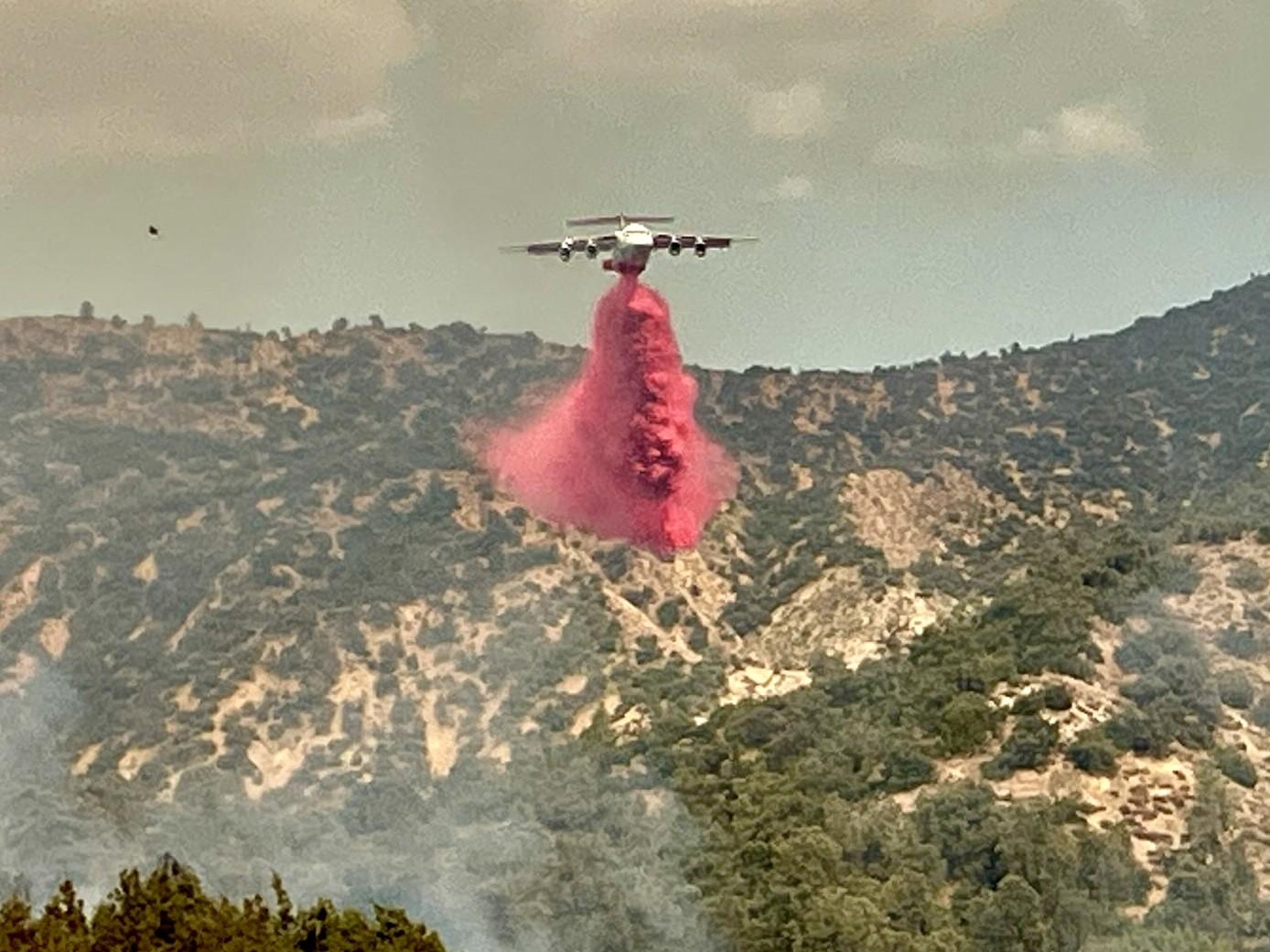 An aircraft drops retardant on the Apache Fire.