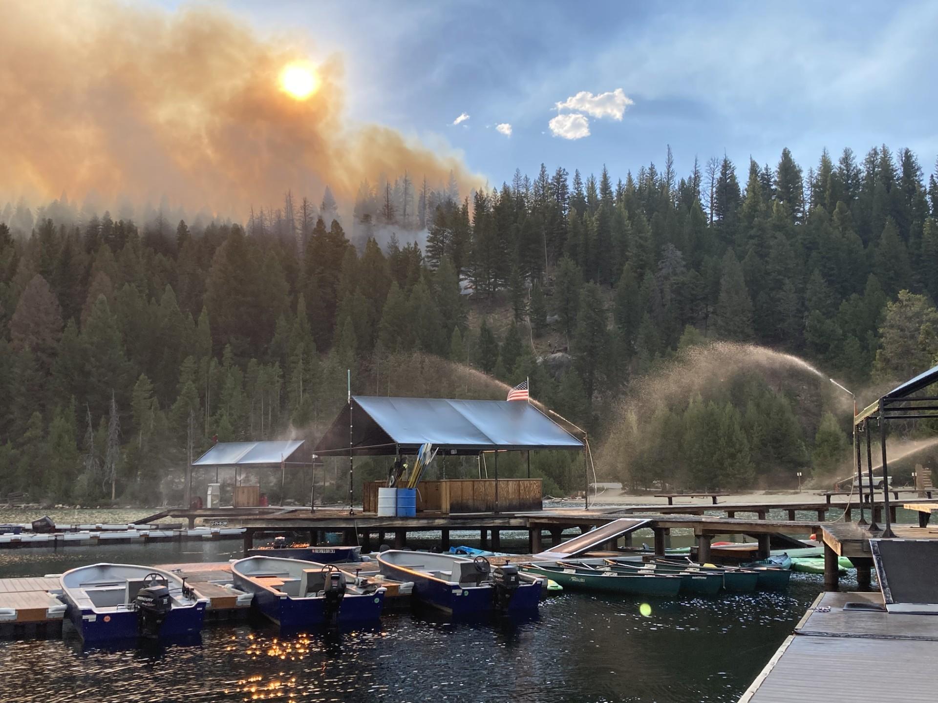 View of boats on the waterfront with hose lays and fire in the background. 