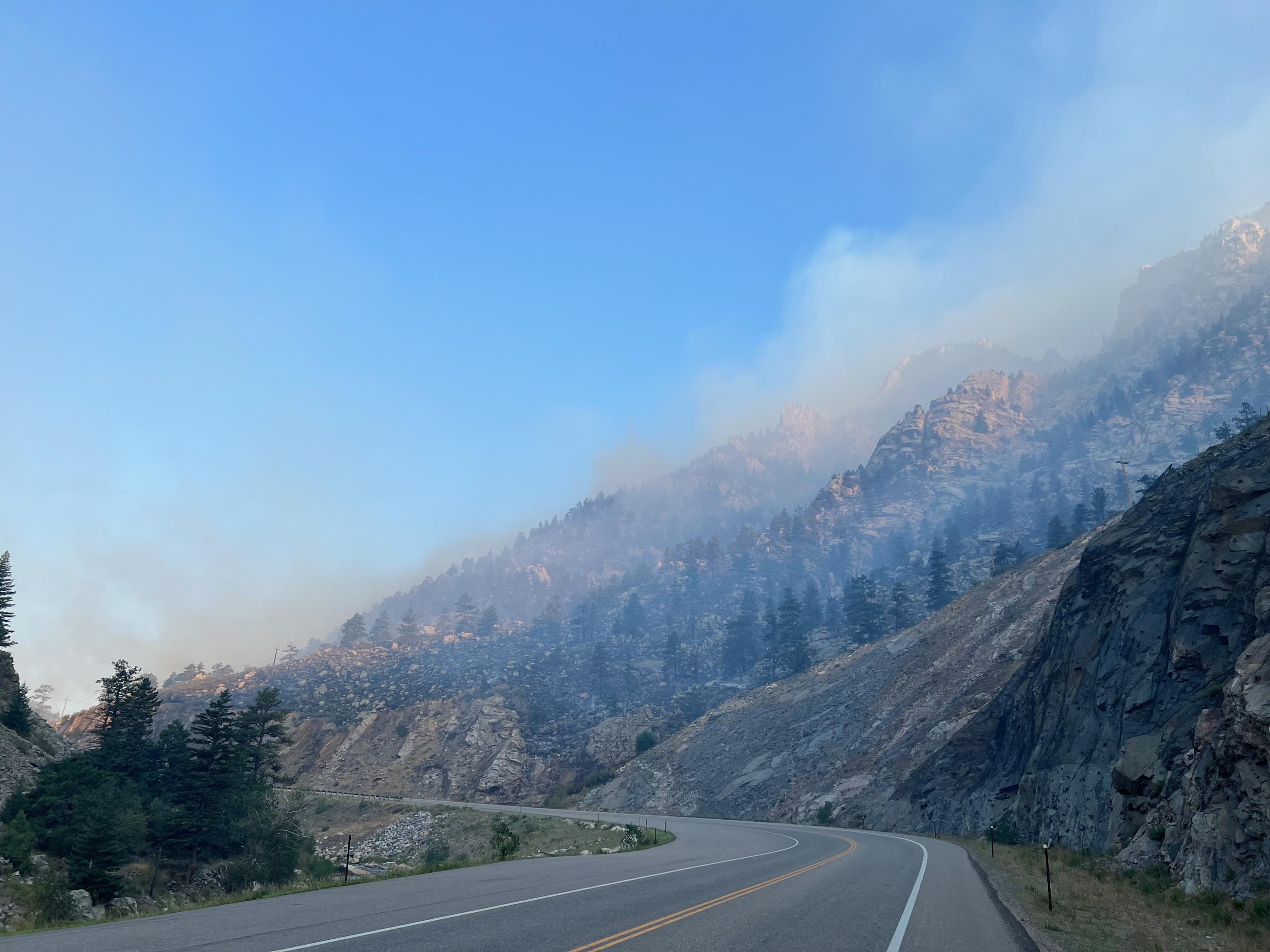 Image shows smokey hillside with Highway 34 in the foreground