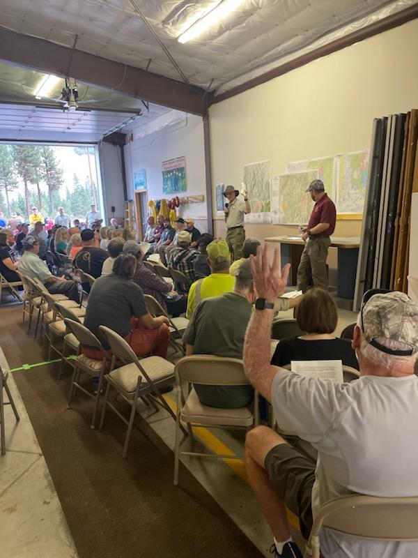 A man raises his hand to ask a question at a community meeting