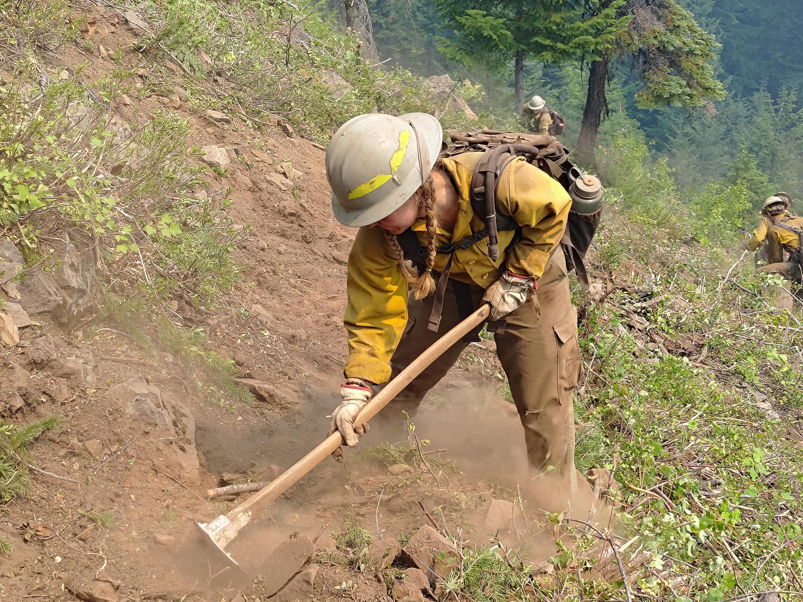 firefighter digging dirt on steep slope