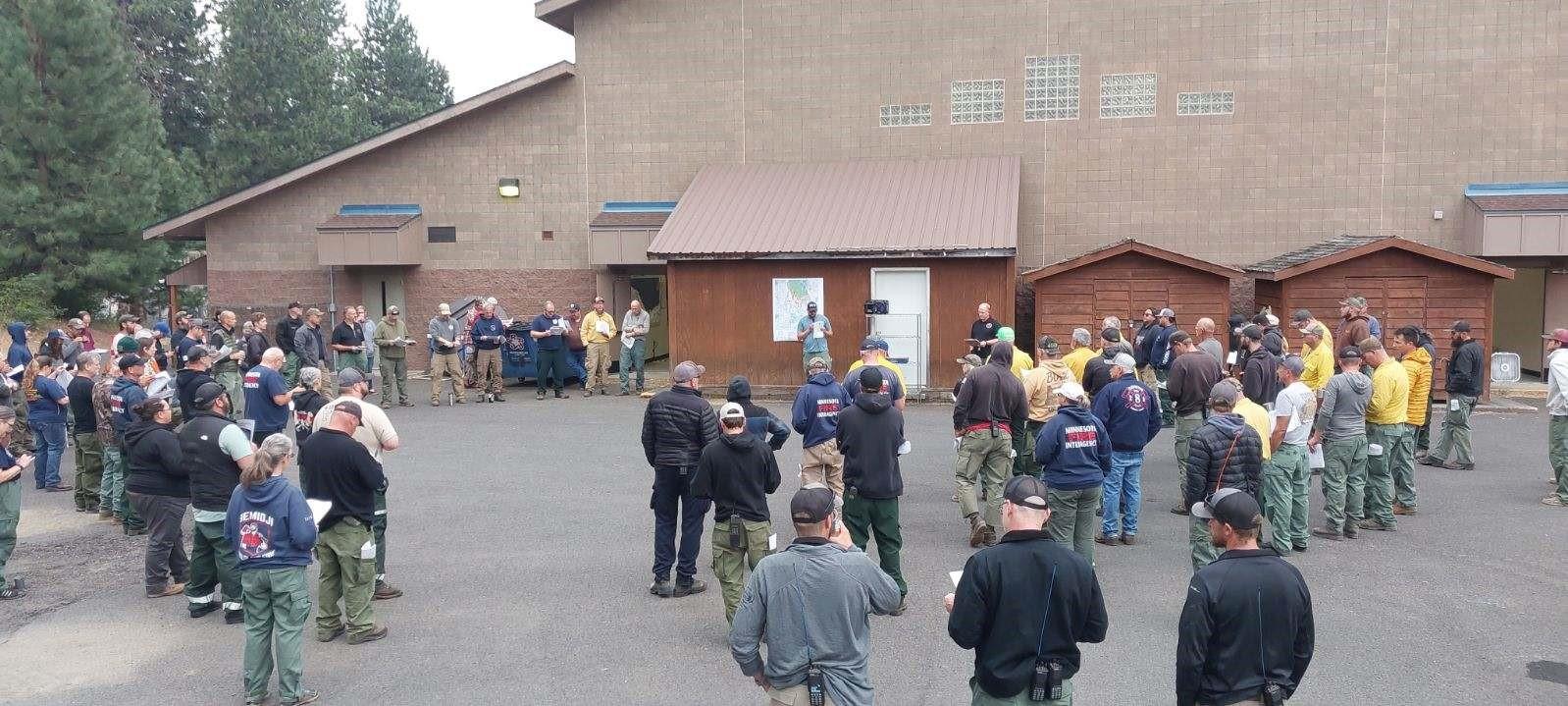 A group of firefighters gathered to listen to outdoor meeting. 