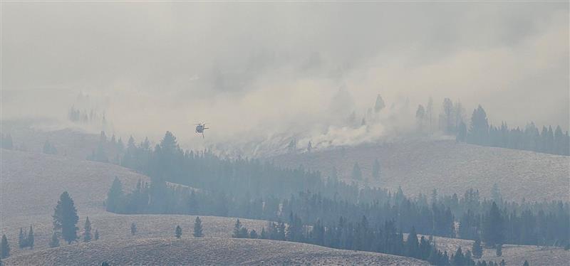 a helicopter flies over fast moving fire