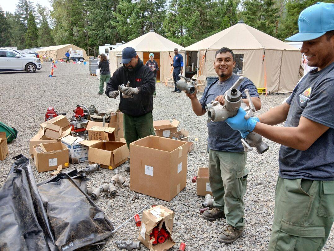 Three crew members are cleaning and packing forestry gated wye hardware for future use.