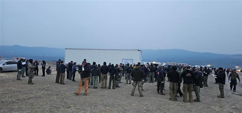 personnel huddle together in the early morning to listen to morning briefing on 8/24