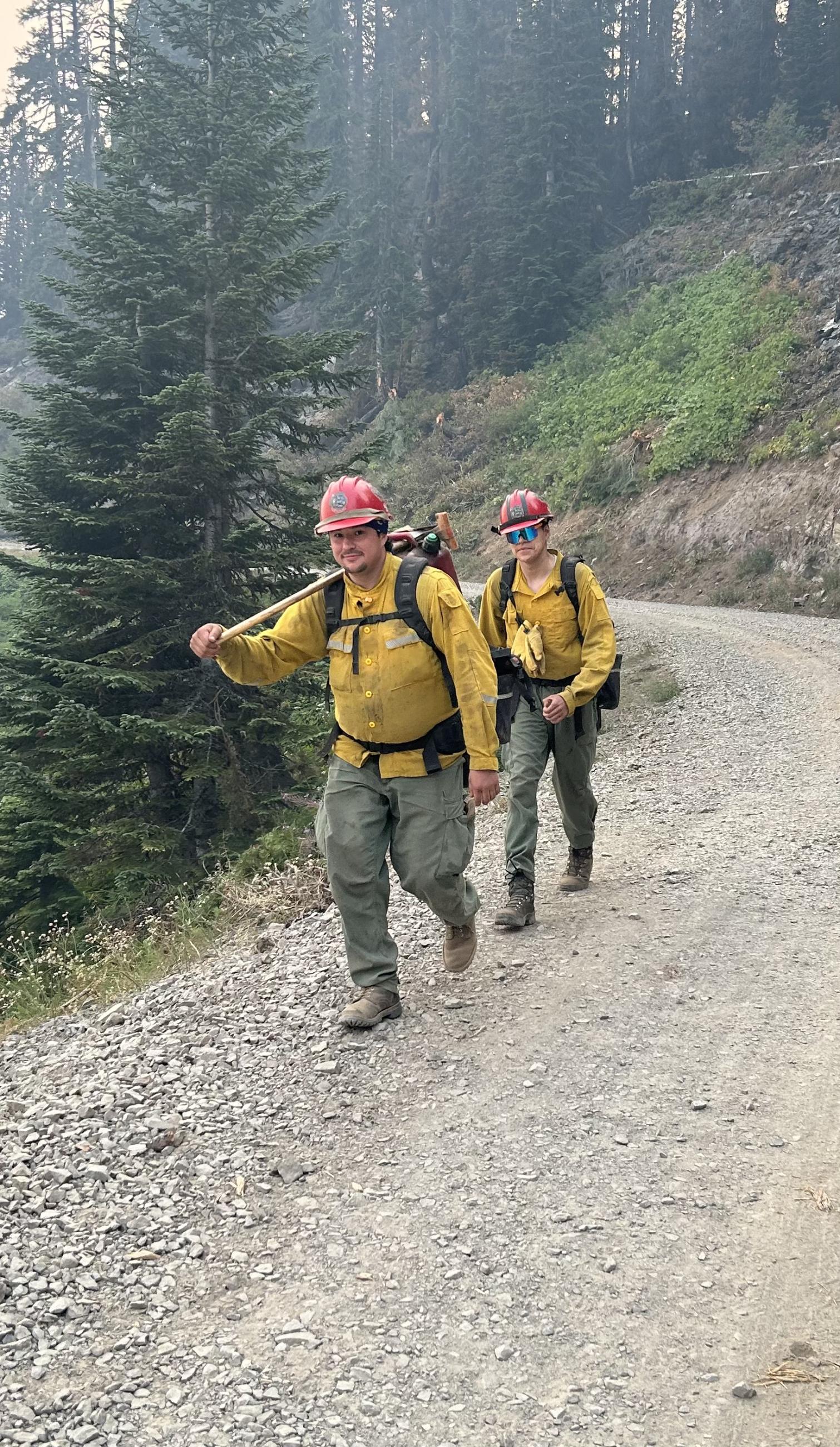 2 firefighters walking along a road