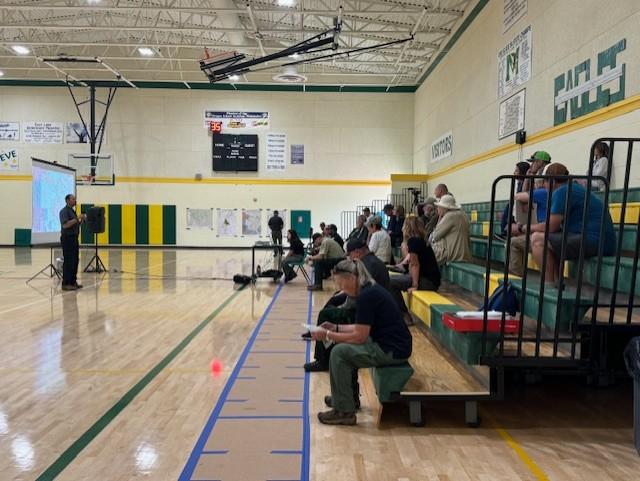 image of a gym, people in stadium seats attending a meeting.