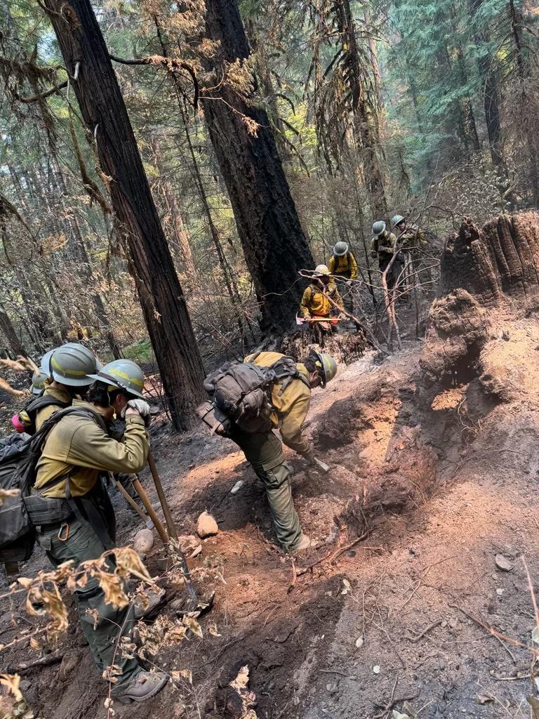 Firefighters around smoking dust with one digging