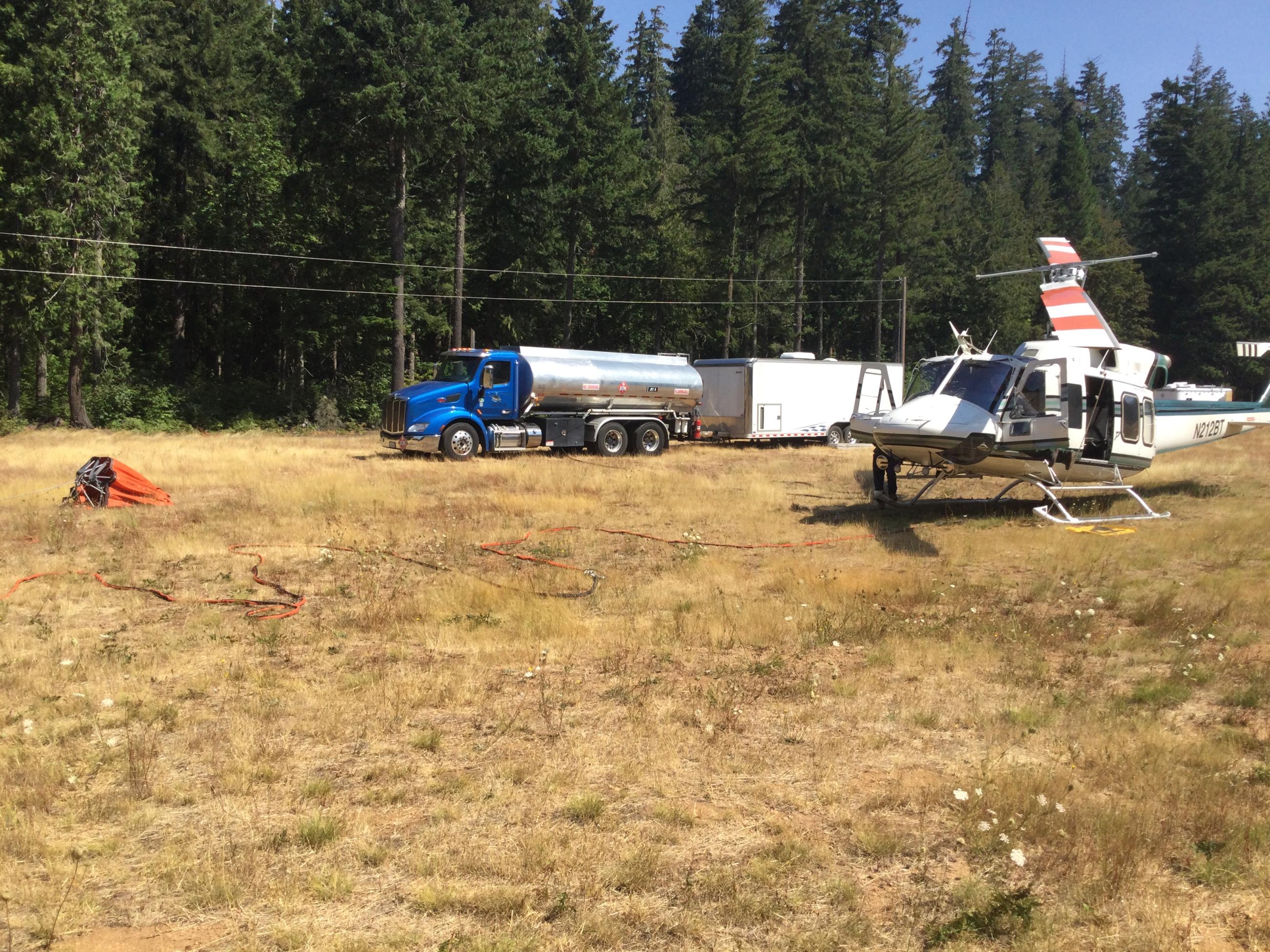 A helicopter with fuel truck nearby