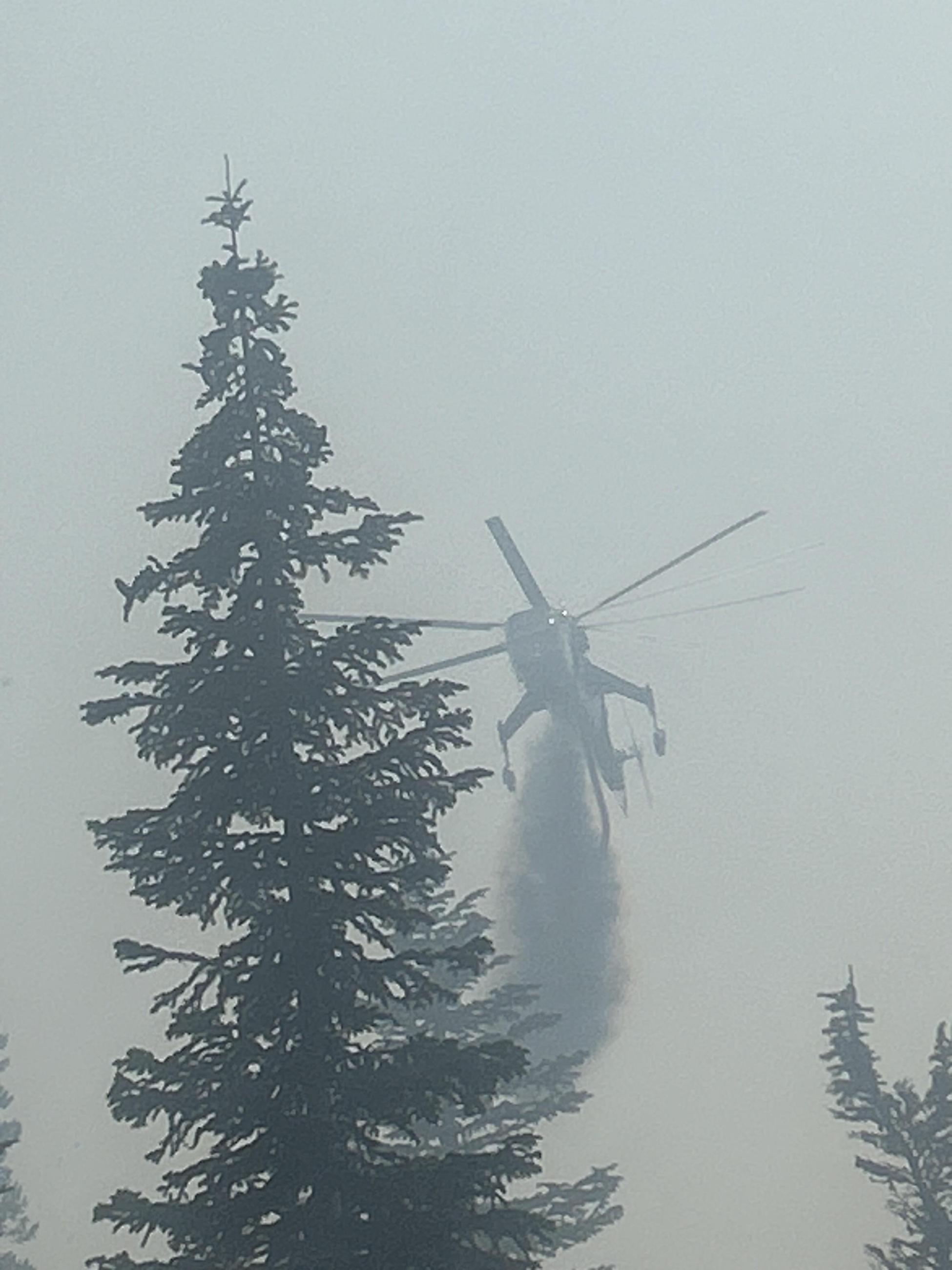 Smokey sky with large helicopter dropping water