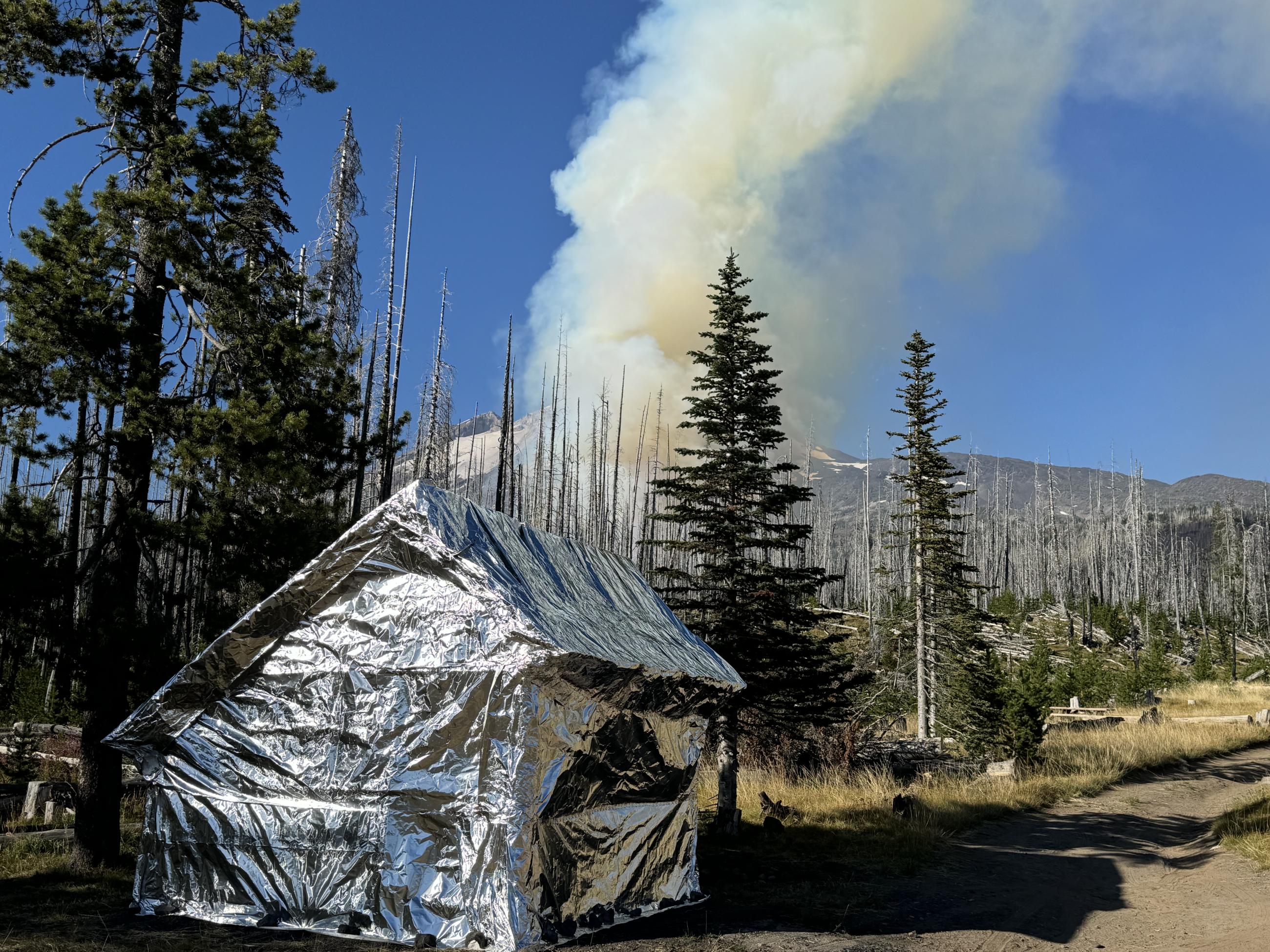 Morrison Shelter wrapped in protective fabric, with smoke in the distance 8-30-24