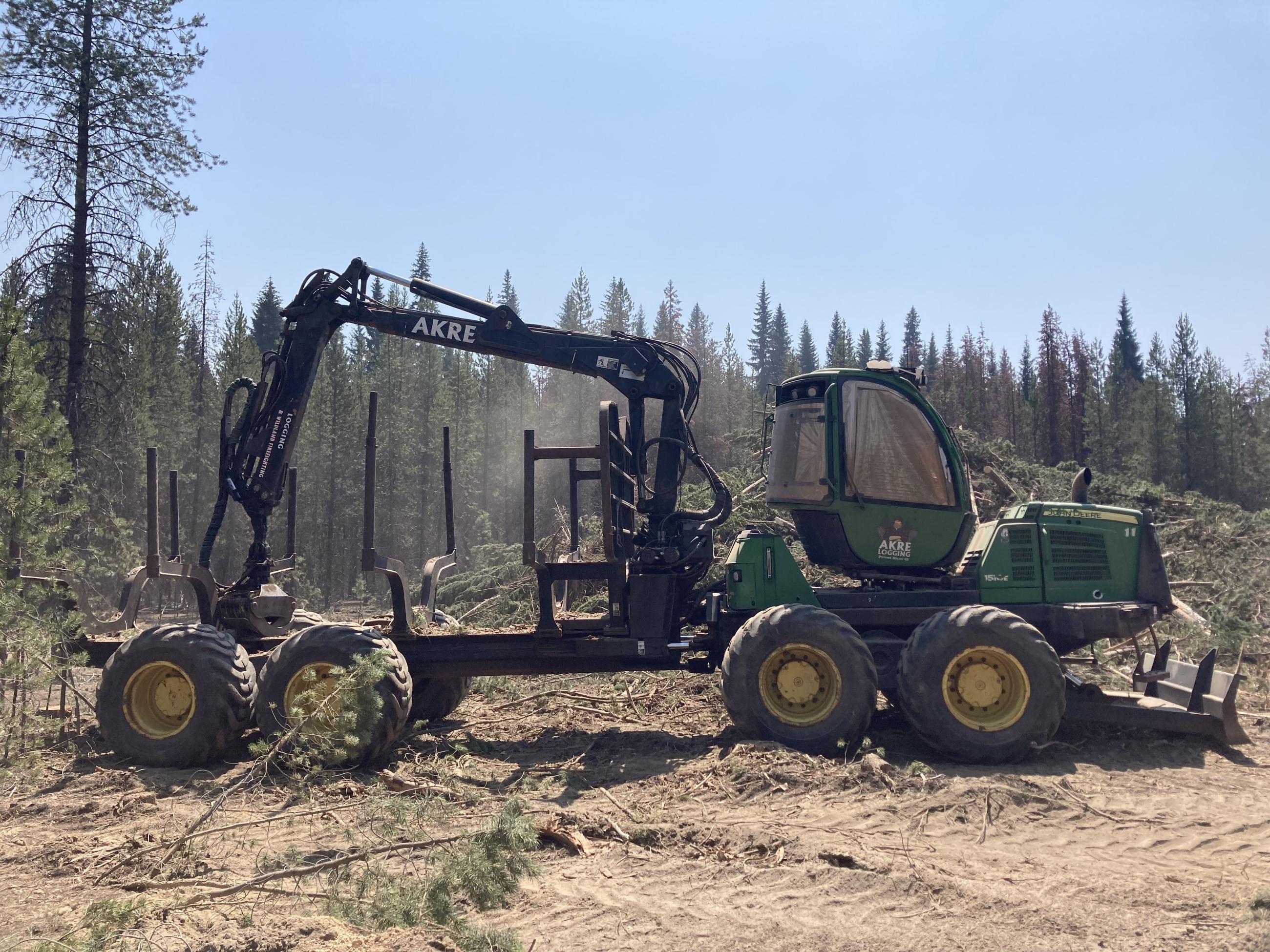 Heavy equipment to load logs removed from shaded fuel break and stack for transport.