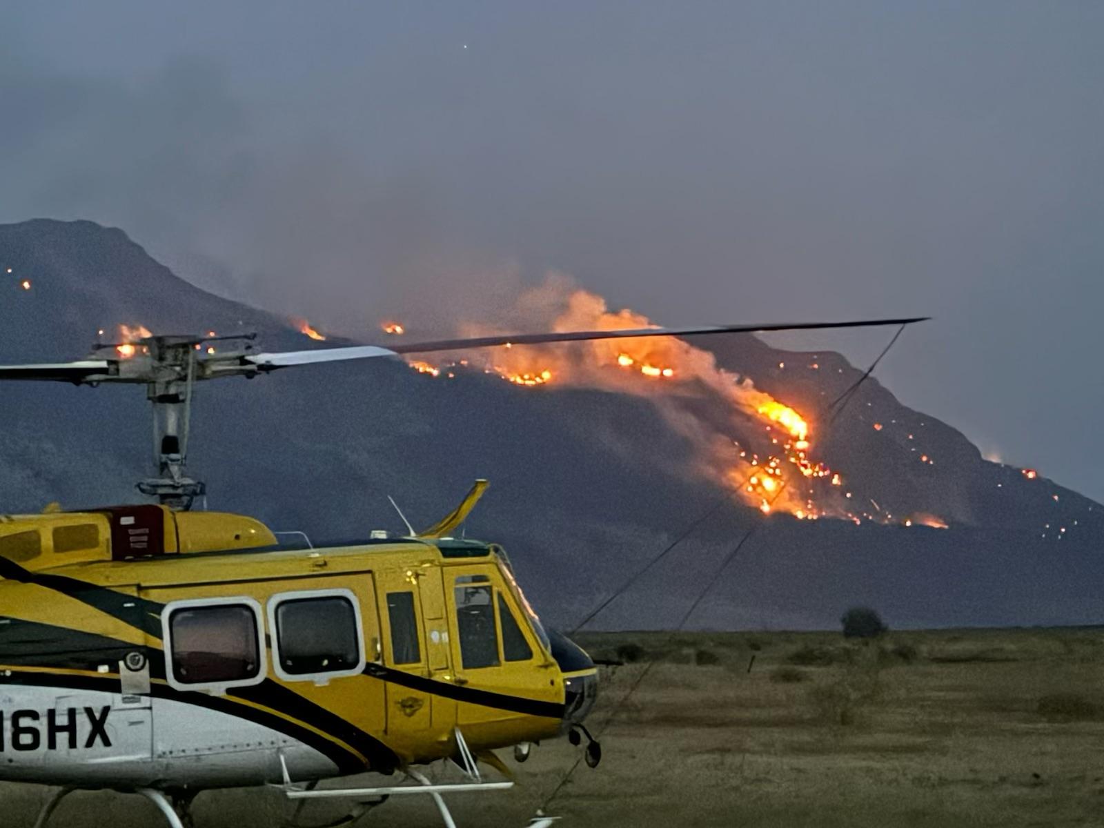 this photo shows a helicopter in the evening in front of the Warner Peak Fire